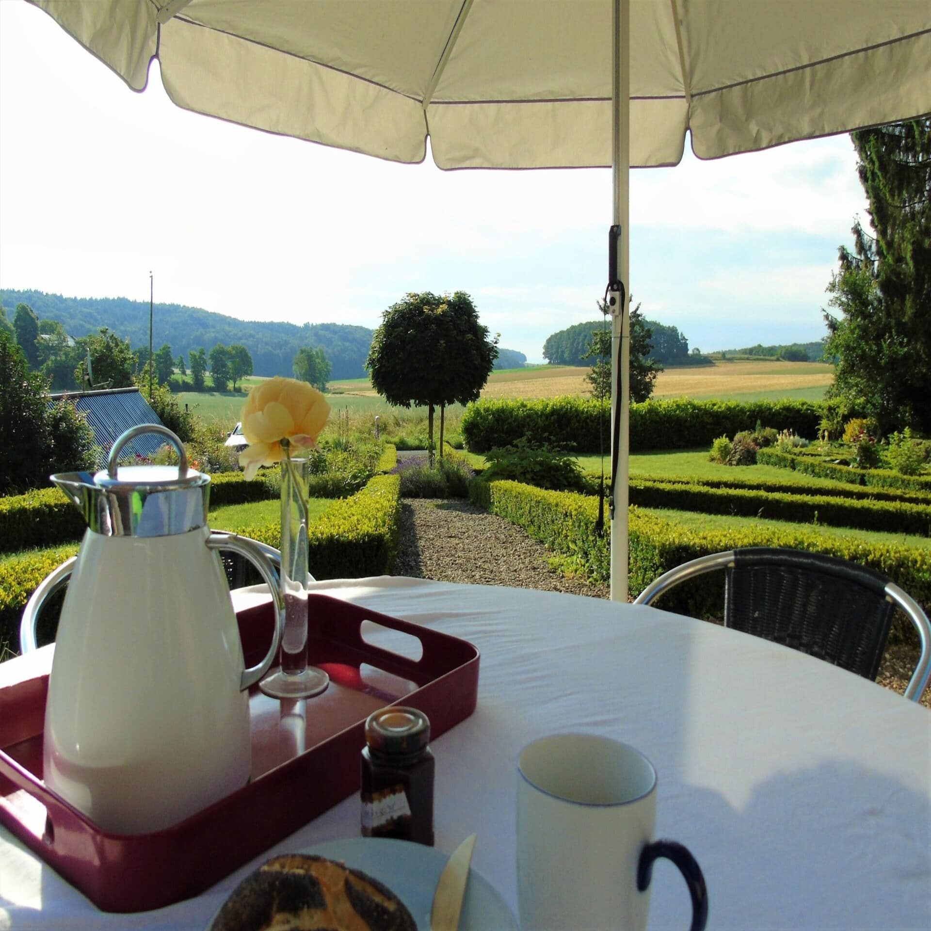 Frühstückstisch im Garten mit Blick auf die ländliche Umgebung.