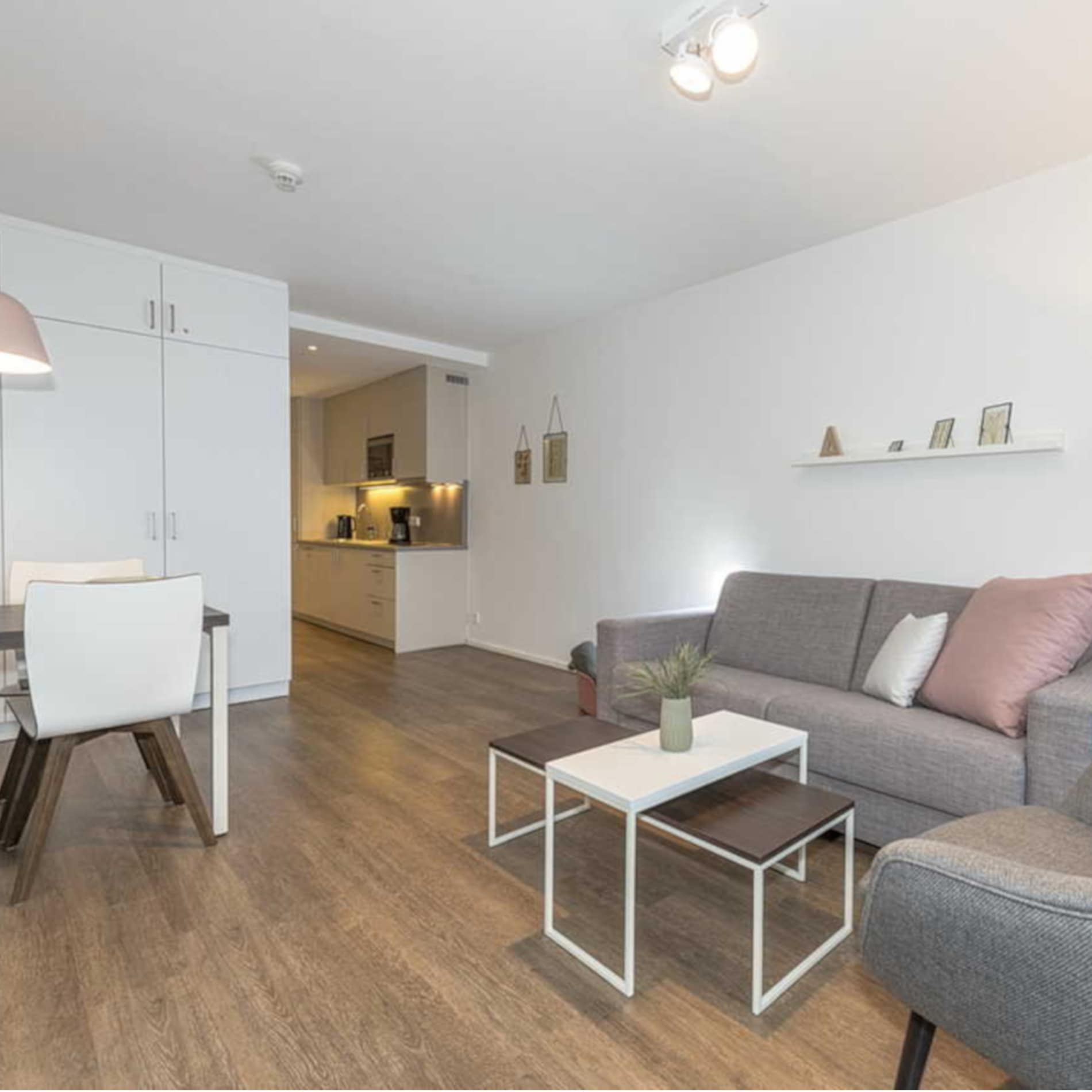 Modern und hell eingerichtetes Wohnzimmer und Kochnische einer Ferienwohnung auf Langeoog