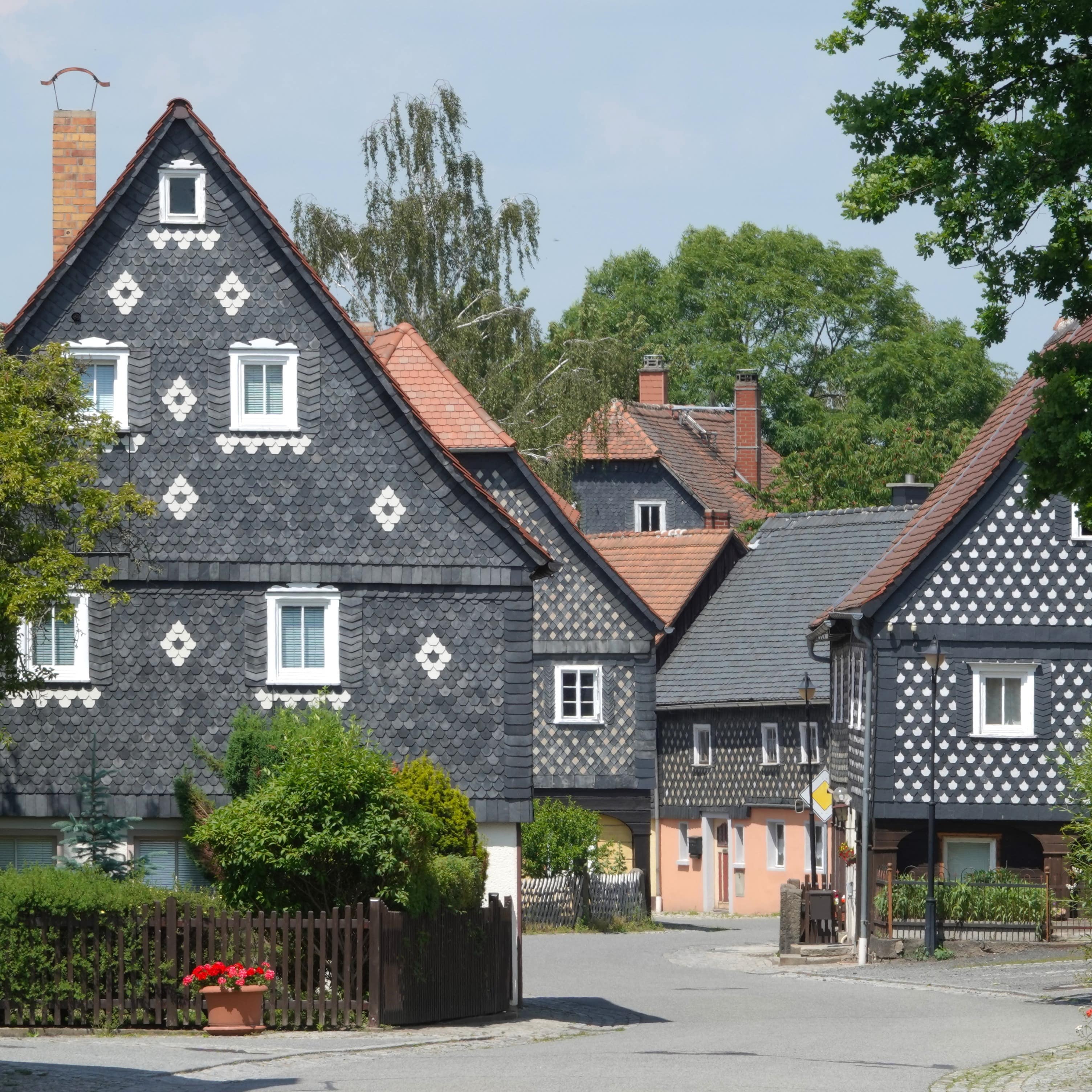 Kleine Straße mit schwarzen Schieferhäusern mit weißen Verzierungen in einem Dorf in Sachsen.