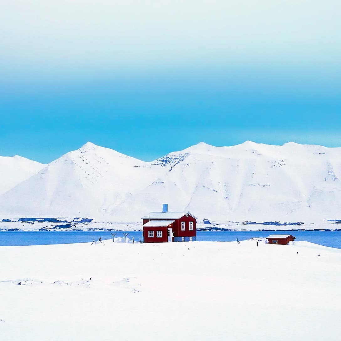 Eine Hütte am See in Skandinavien inmitten einer verschneiten Landschaft 