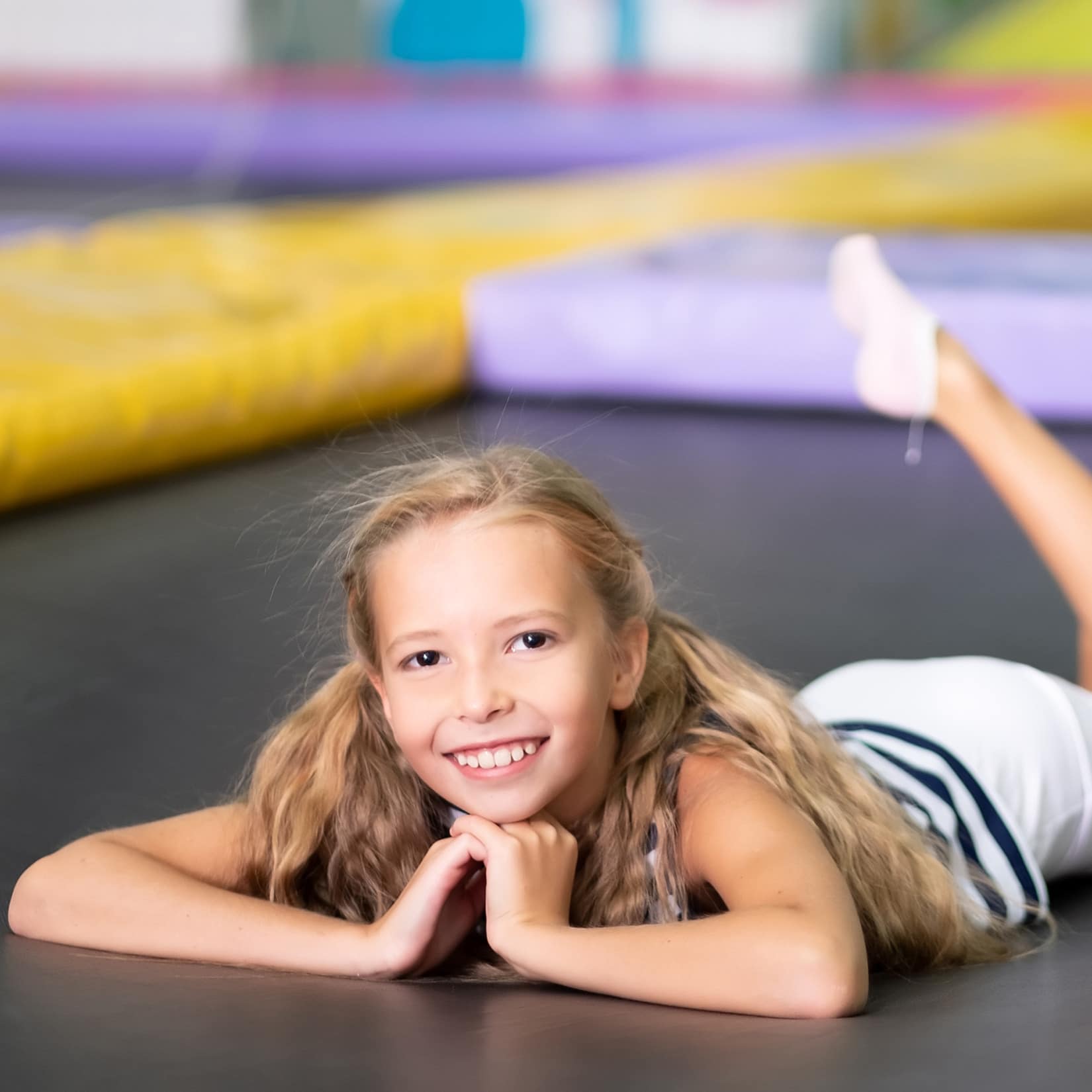 Ein Mädchen liegt auf einem Trampolin.