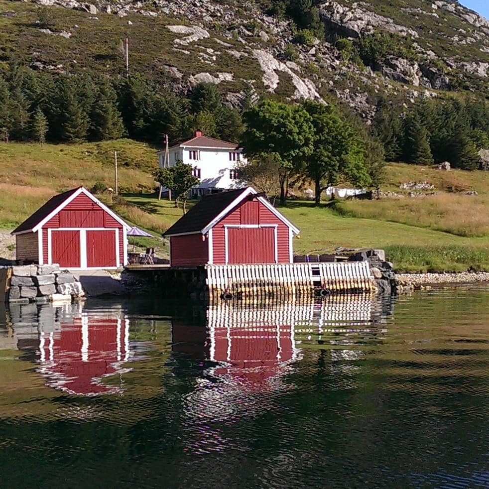 Ansicht auf ein Ferienhaus am Fjord mit eigenem Bootshaus und Anleger