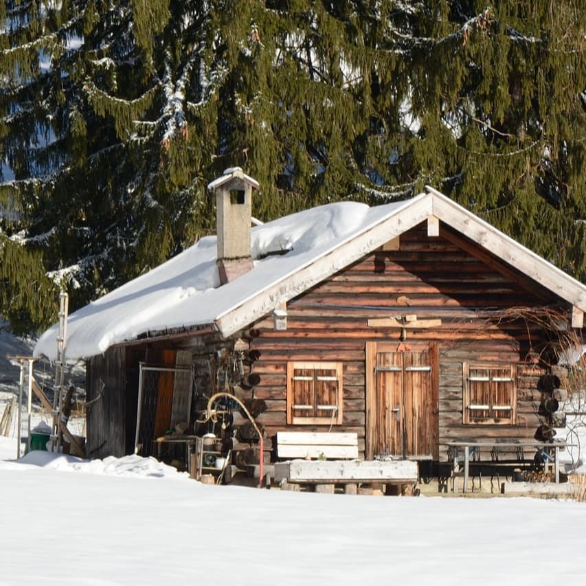 Eine frei stehende Holzhütte inmitten einer verschneiten Winterlandschaft