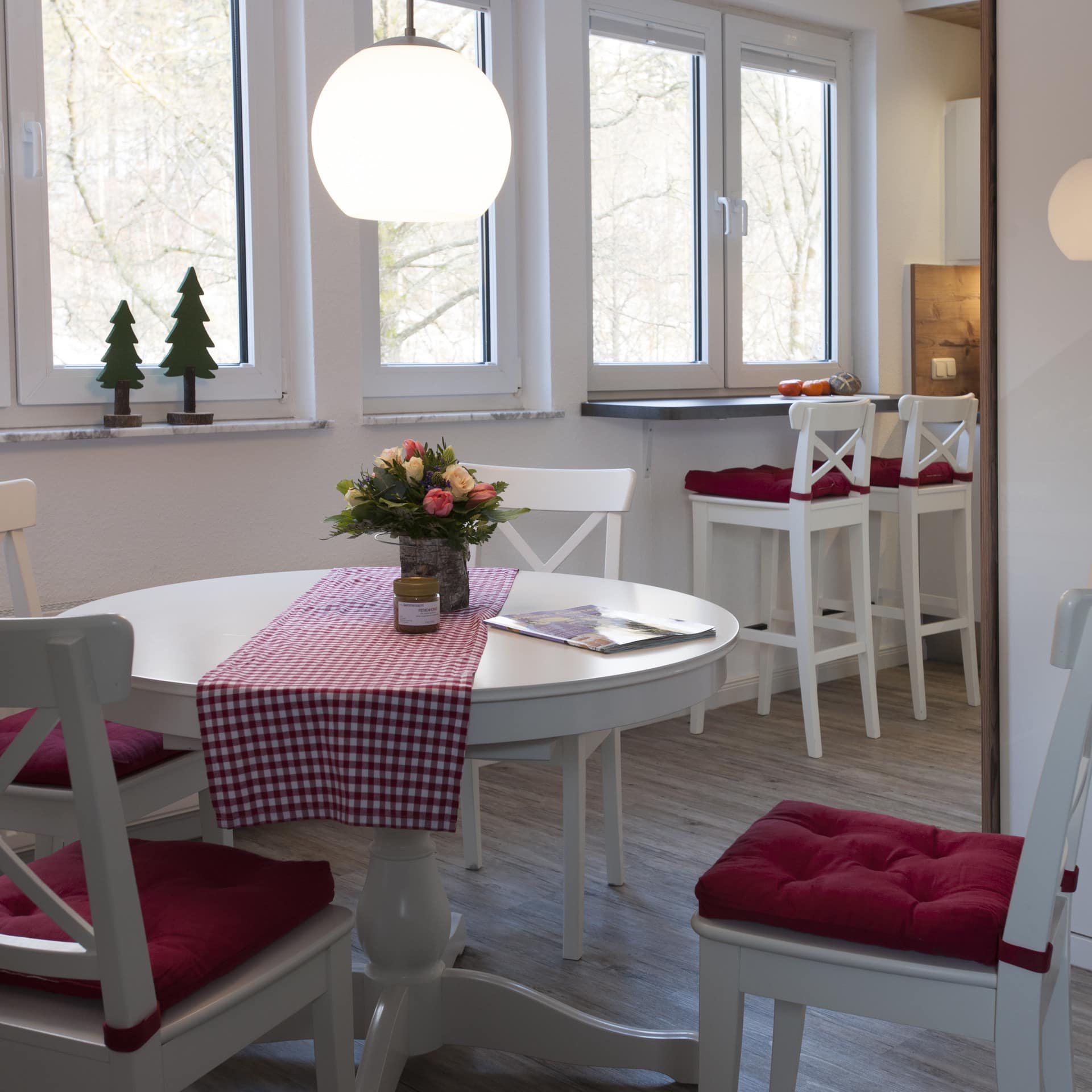 Ferienwohnung in Braunlage mit gemütlicher Wohnküche mit hellen Möbeln und roten Sitzpolstern