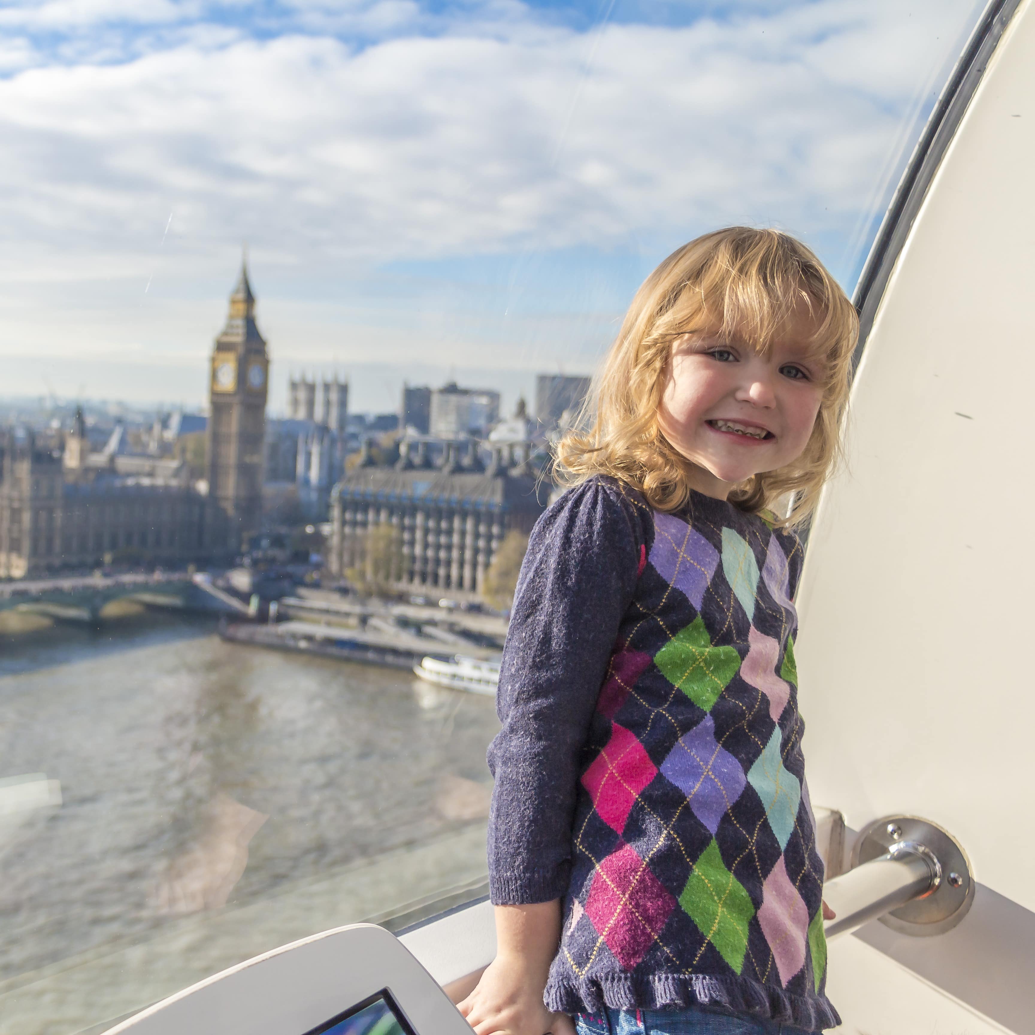 Mädchen in Pulli und Jeans in einer Kabine des London Eye, die Themse, Big Ben und die Houses of Parliament sind zu sehen.