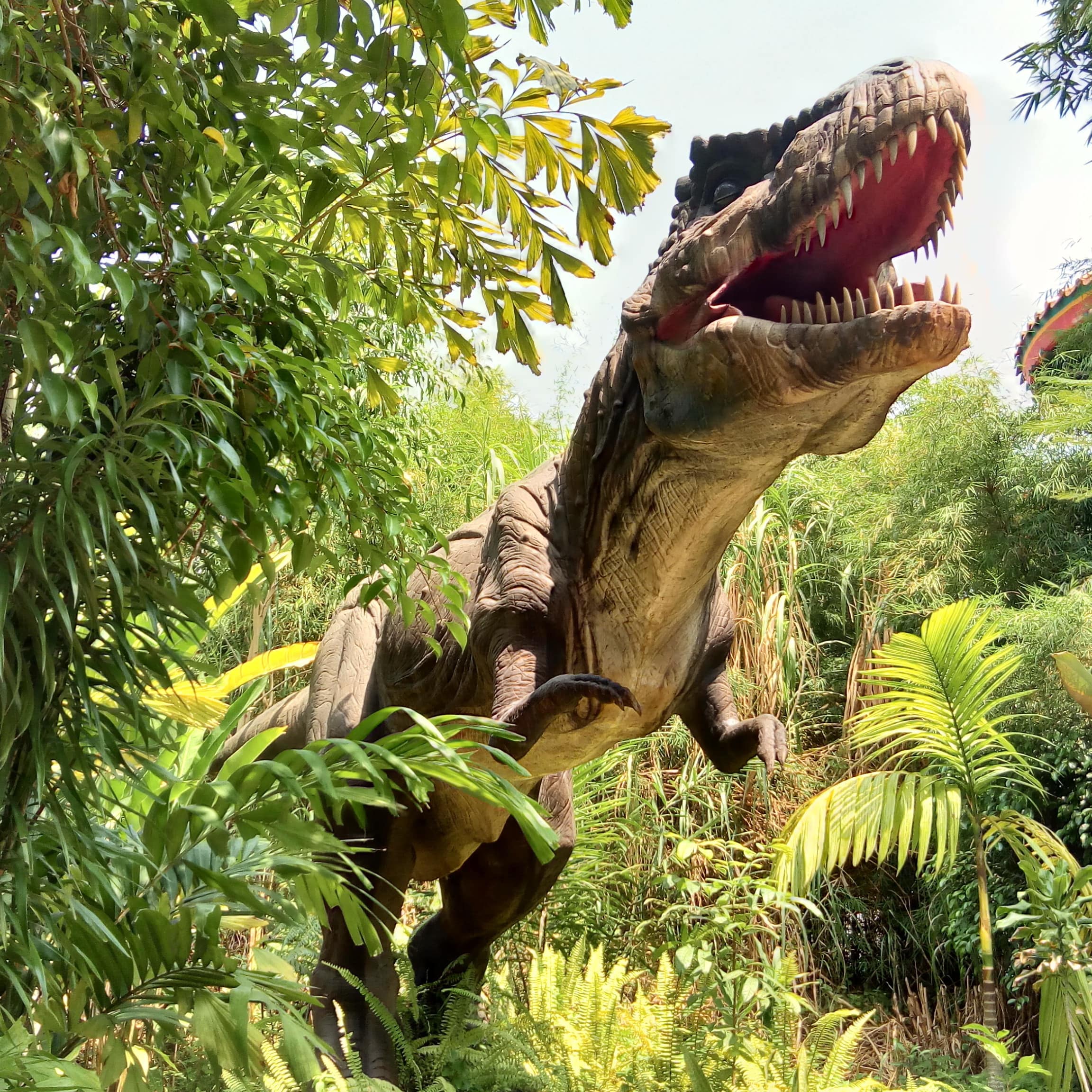 Eine T-Rex Figur in einem Dschungel.
