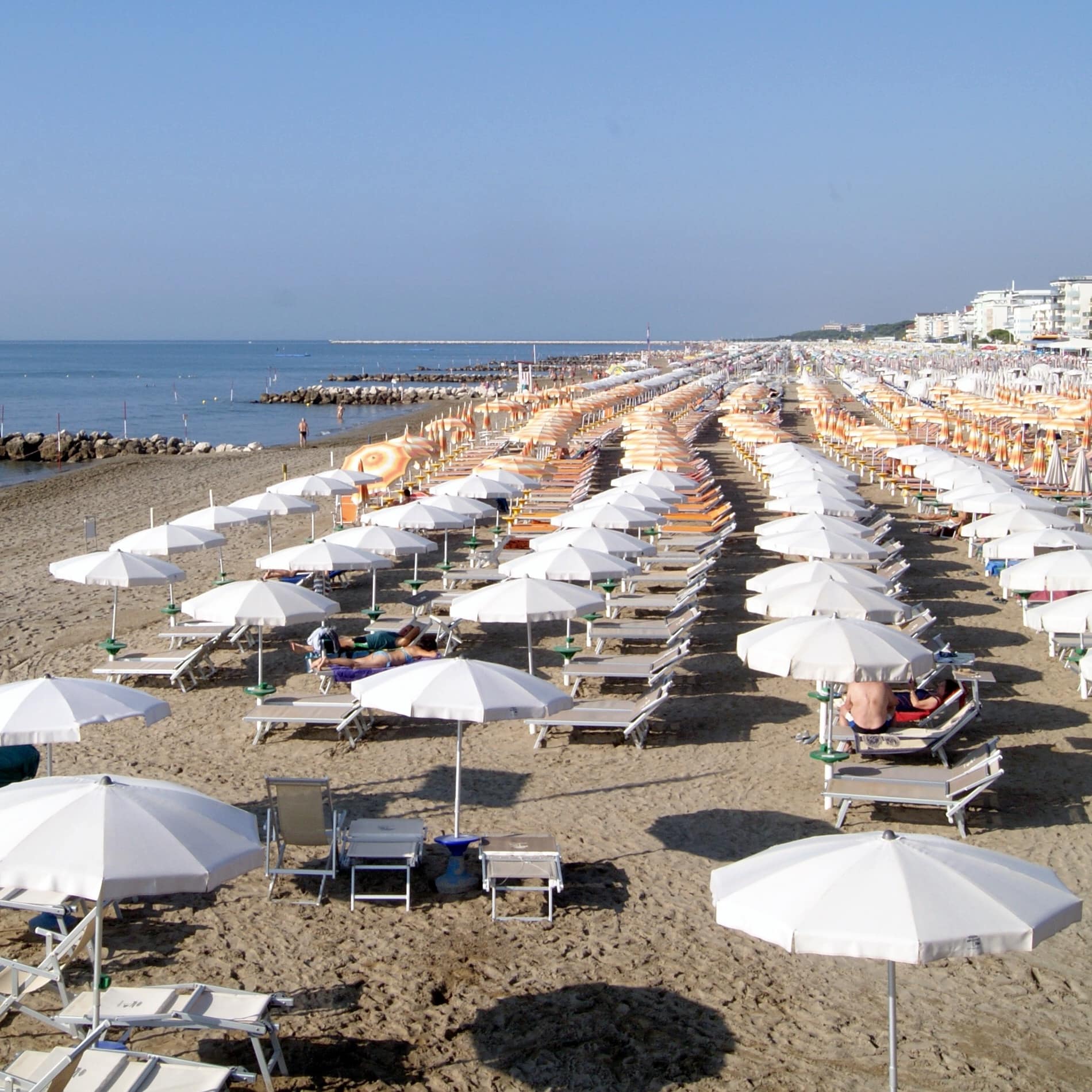 Am Sandstrand von Caorle in der Region Venetien reihen sich die Sonnenschirme in langen Reihen bis zum Horizont