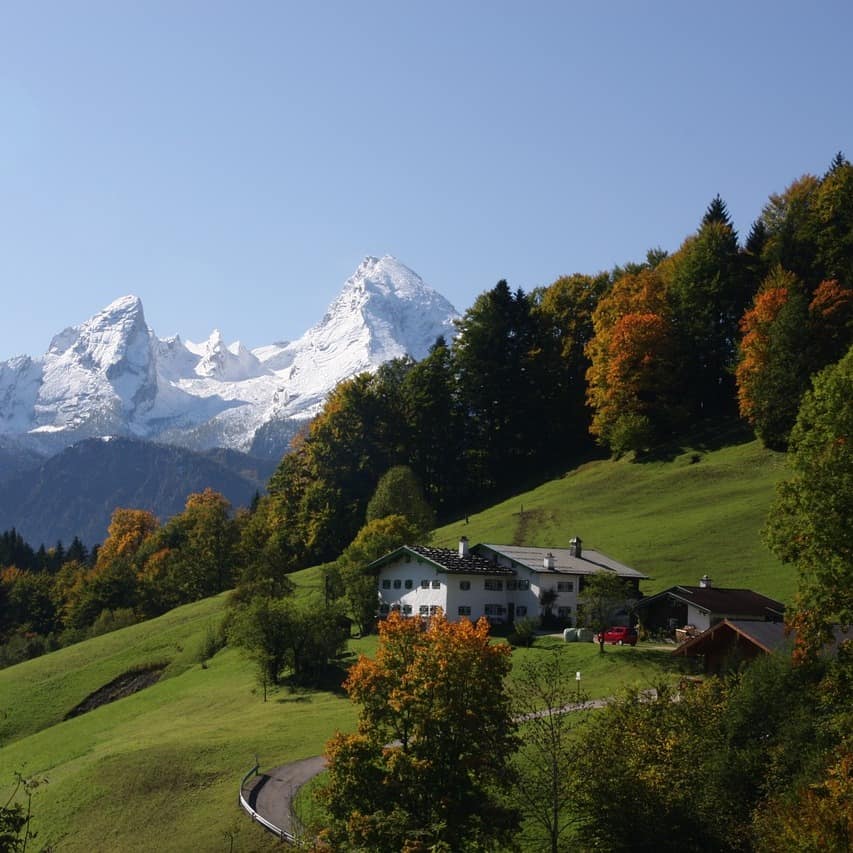 Dieser Berghof bietet Ferienwohnungen und Gästezimmer, von denen Sie weit ins Land blicken können. Im Hintergrund strahlt der weiße Gipfel des Watzmanns, dem höchsten Berg der Region.