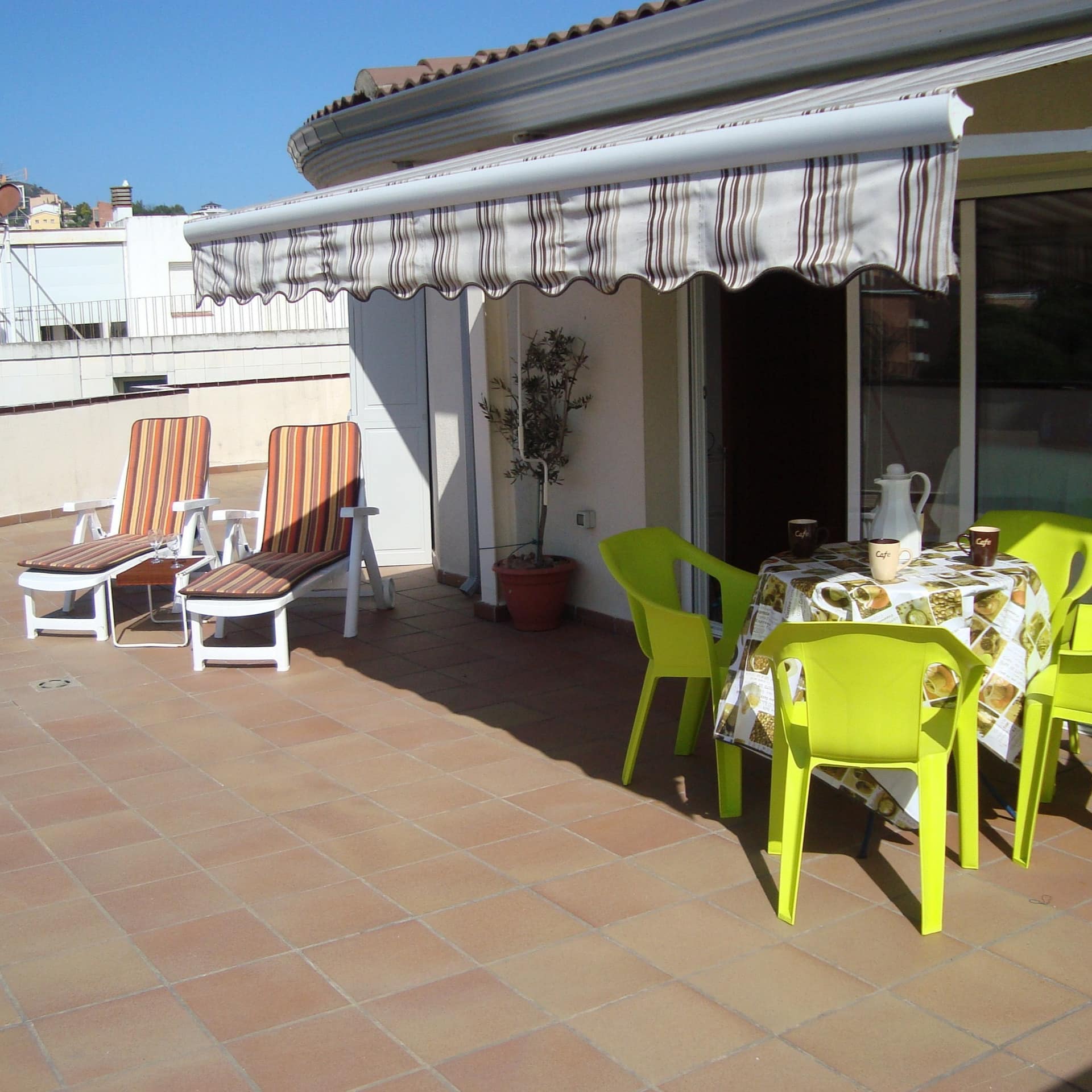 Ferienwohnung an der Costa Brava im Dachgeschoss mit großer Terrasse, darauf Tisch, Stühle und Liegen