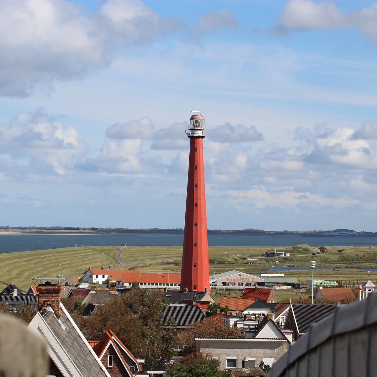 Blick auf einen holländischen Ort und einen Leuchtturm direkt am Wasser