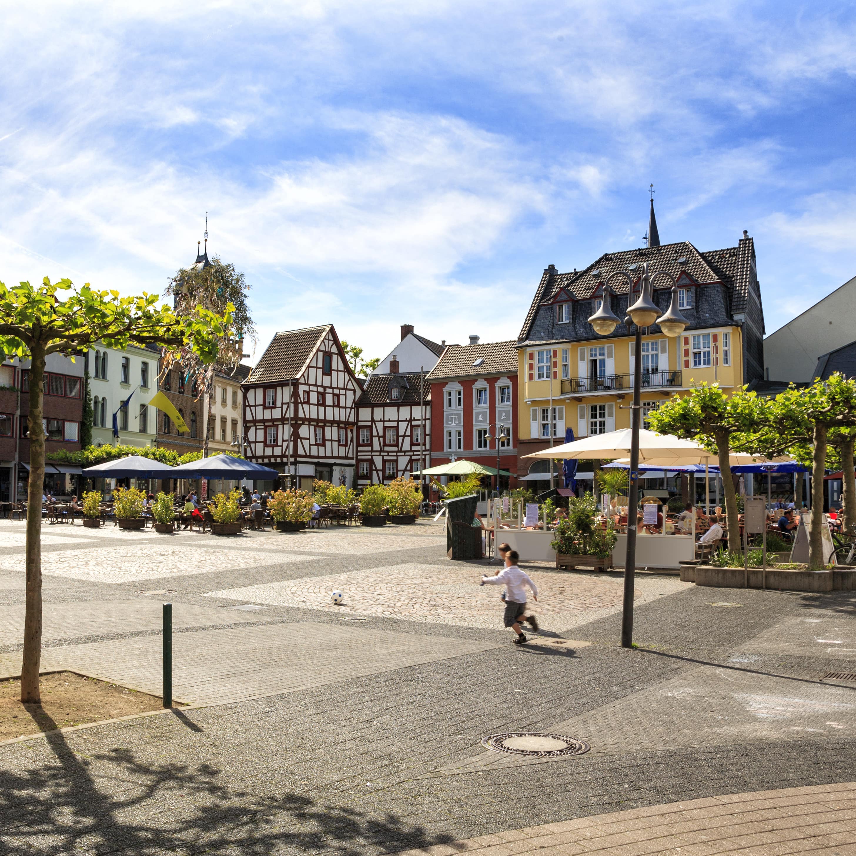 Ein Dorfplatz in einem Ort in der Eifel, ein Junge rennt über den Platz.