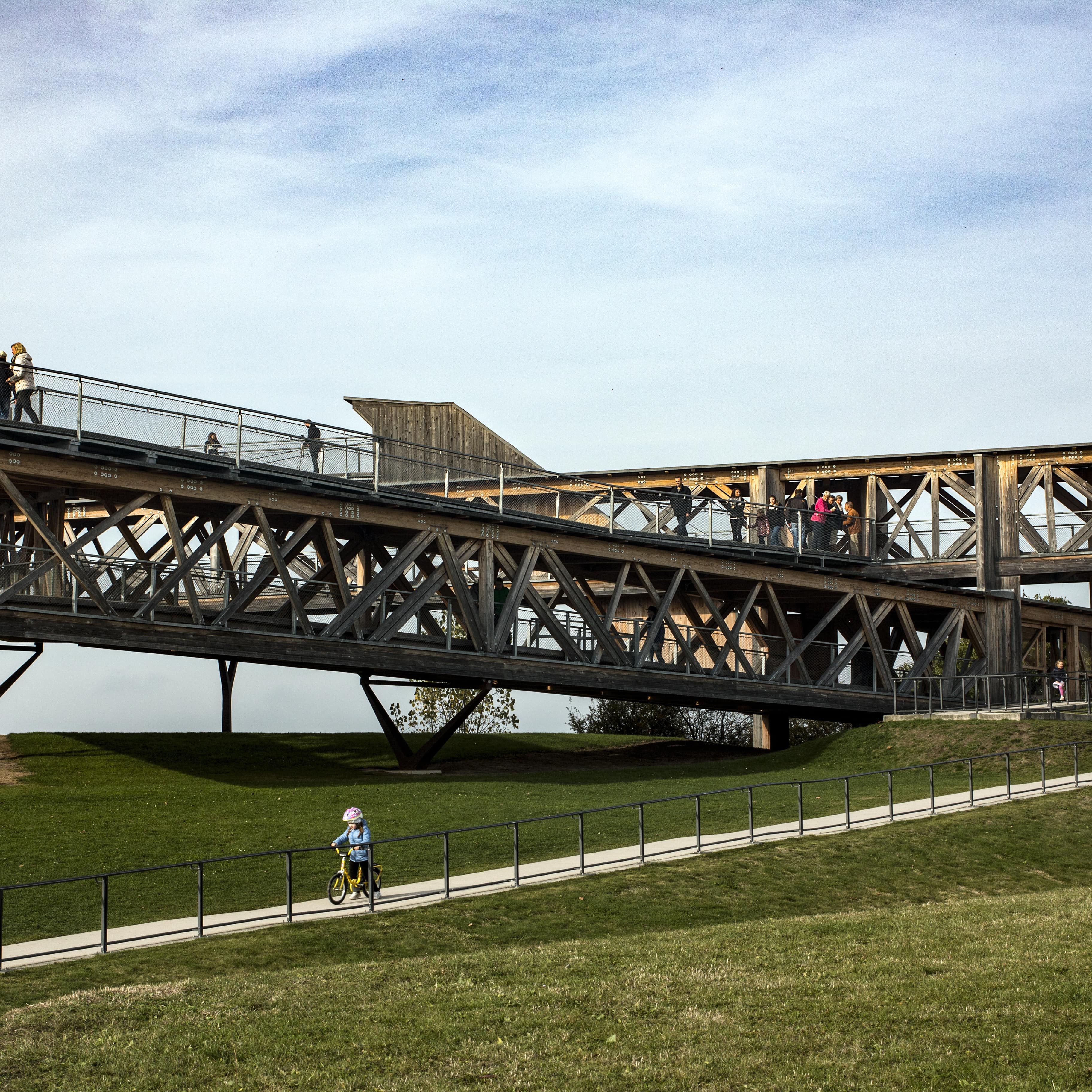 Erhöhte Aussichtsplattform im Grünen in Koblenz, ein kleines Kind mit Laufrad fährt den Weg hinunter.