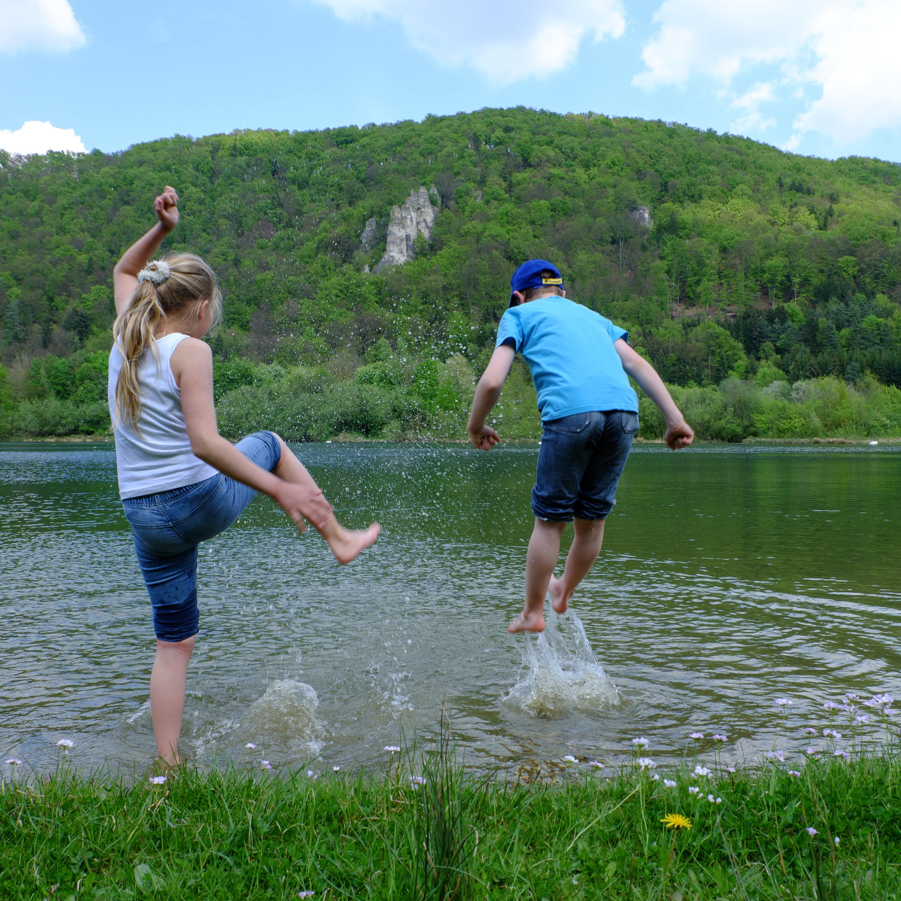 2 Kinder im Sommerkleidung erfrischen sich im Wasser im Altmühltal.