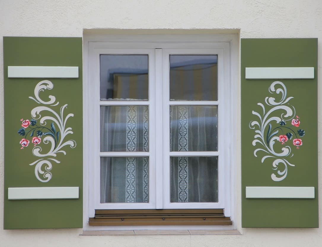 Detailaufnahme der kunstvoll bemalten Fensterläden eines Hauses. 