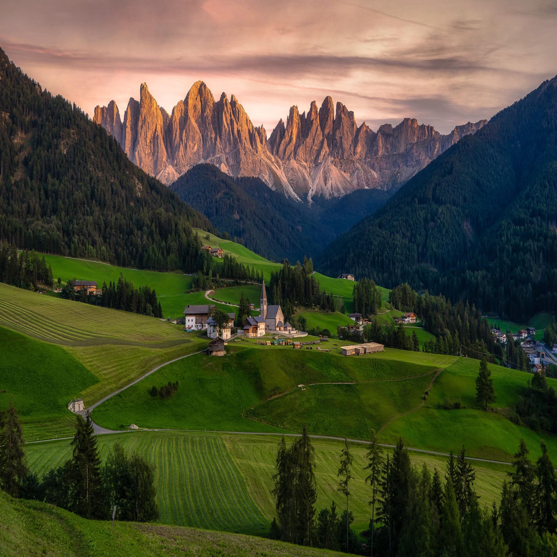 Panoramablick auf ein Dorf in Südtirol zwischen grünen Wiesen, Wäldern und Bergen. 