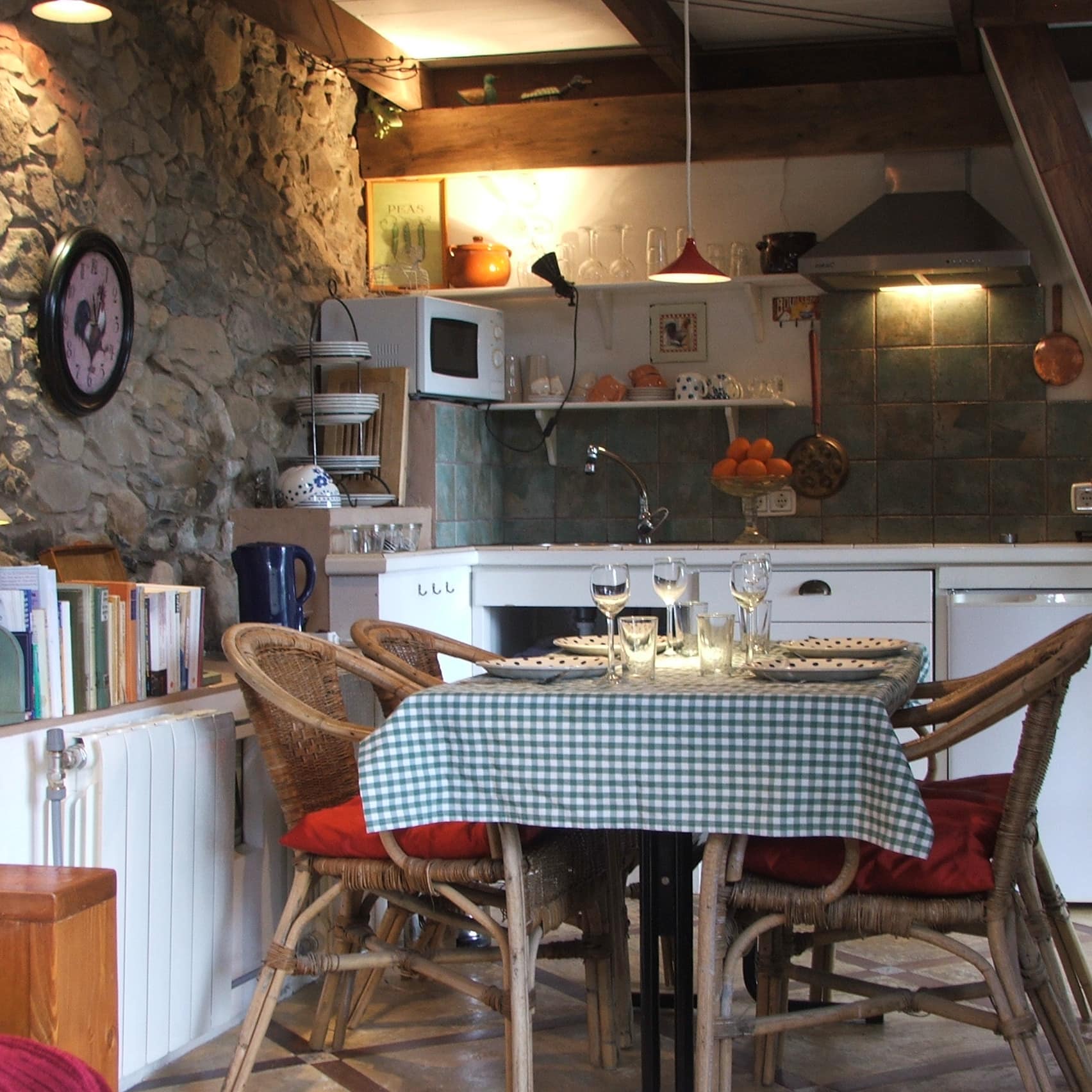 Ferienwohnung auf Gran Canaria mit gemütlicher Wohnküche mit gedecktem Tisch und Stühlen, Bücherregalen und Steinwänden