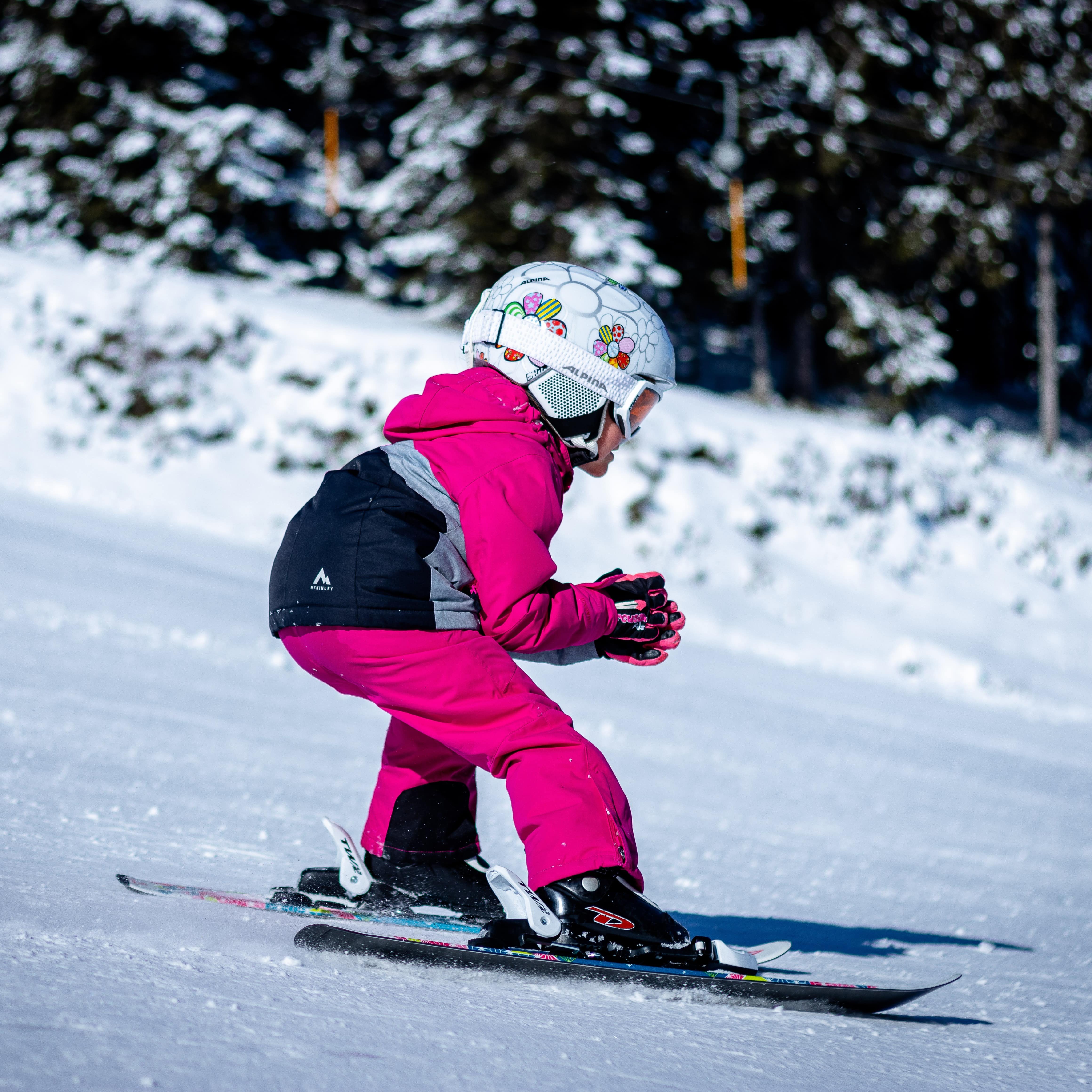 Ein Mädchen auf Skiern fährt einen Hang hinab.