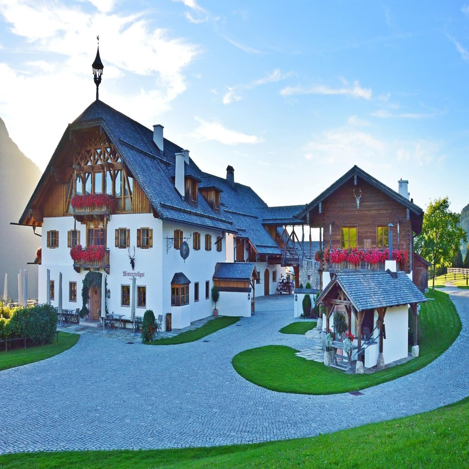 Großes weißes Bauernhaus mit Holzverkleidung und großem Vorhof.