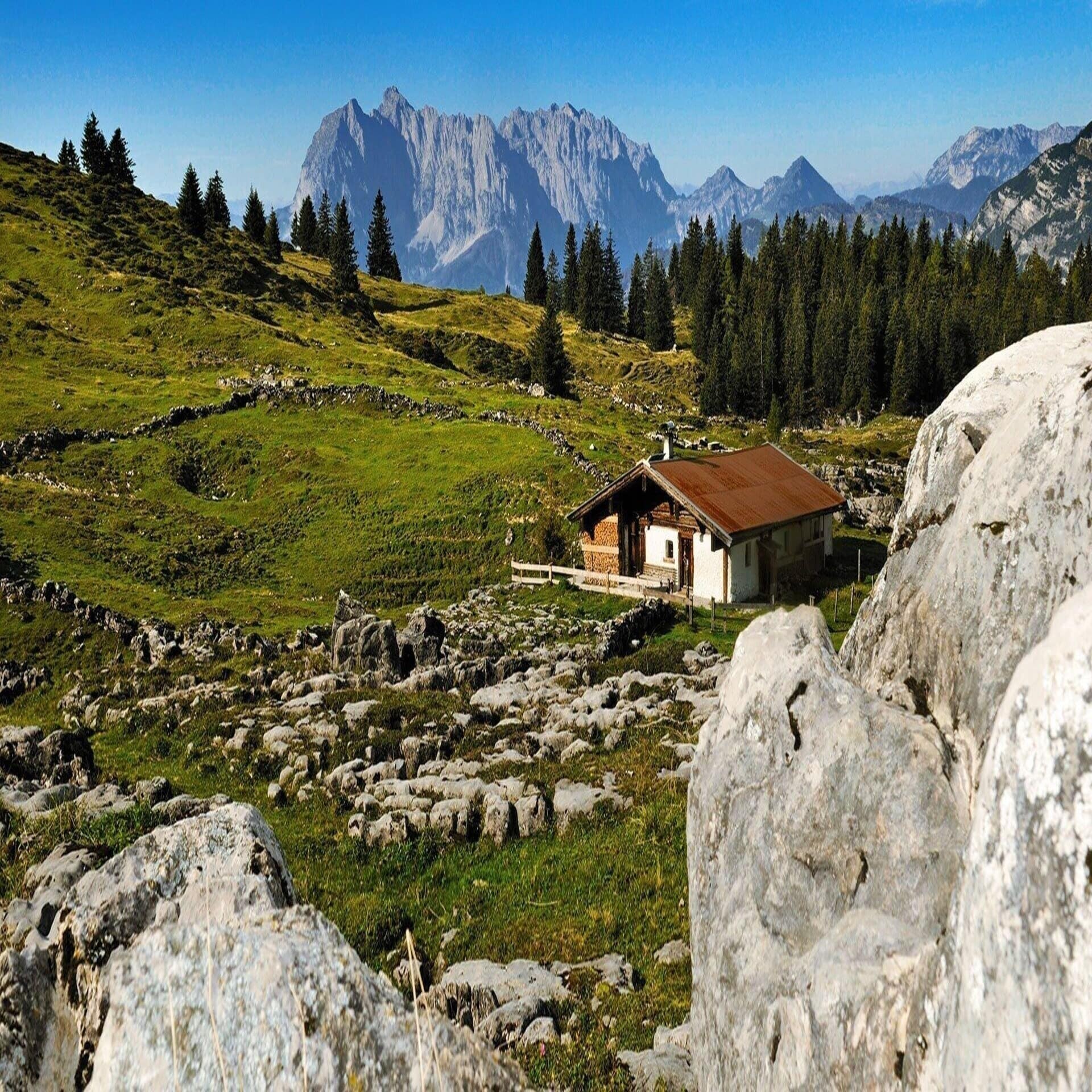 Panoramablick über die sommerlichen Chiemgauer Alpen und eine Hütte.