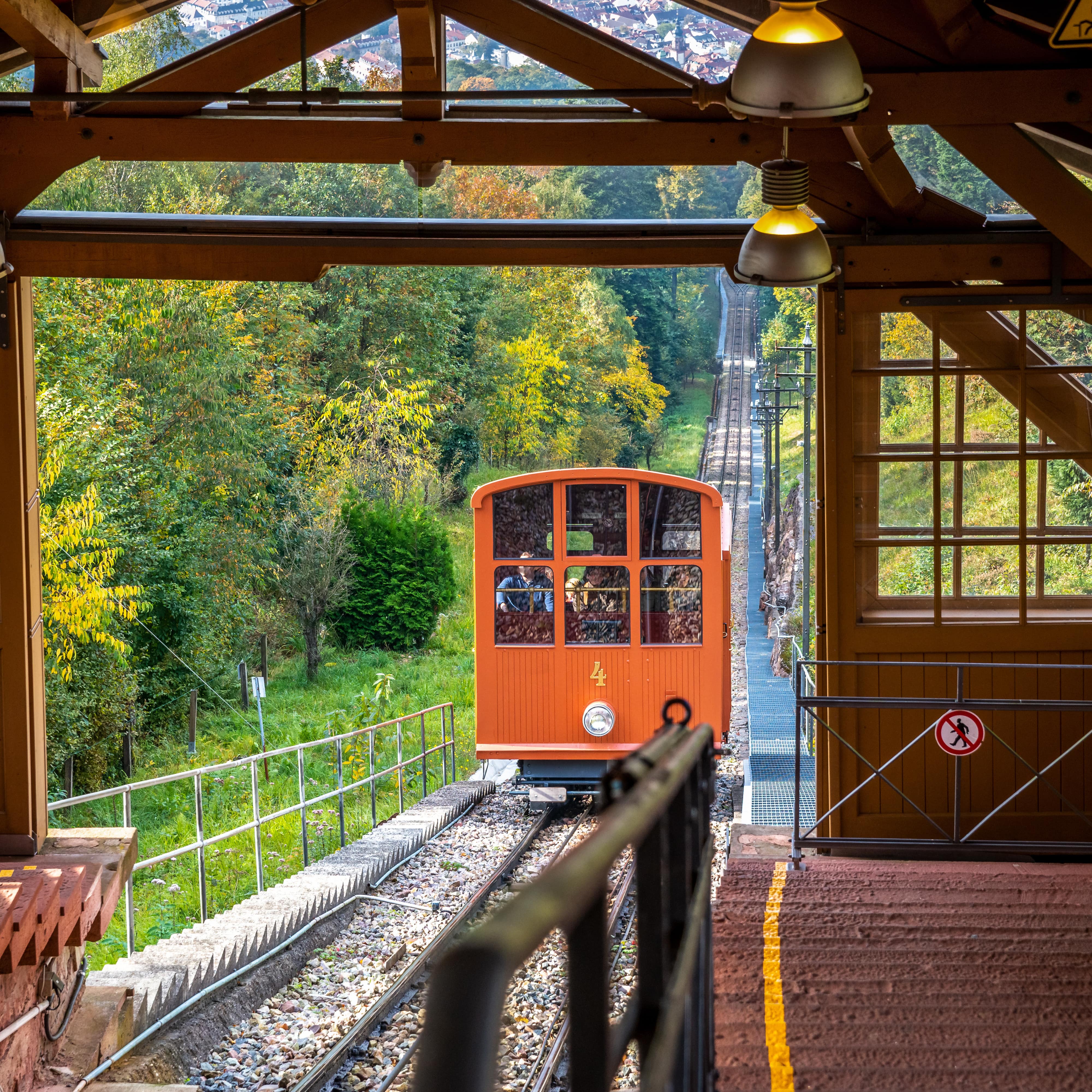 Die orangefarbene Bergbahn fährt in die hölzerne Bergstation ein.