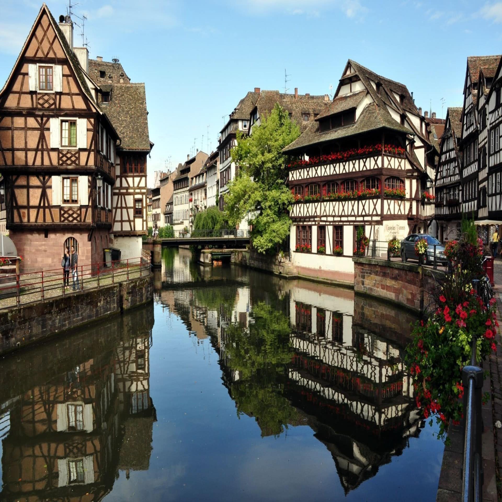 Fachwerkhäuser direkt am Fluss spiegeln sich im Wasser. 