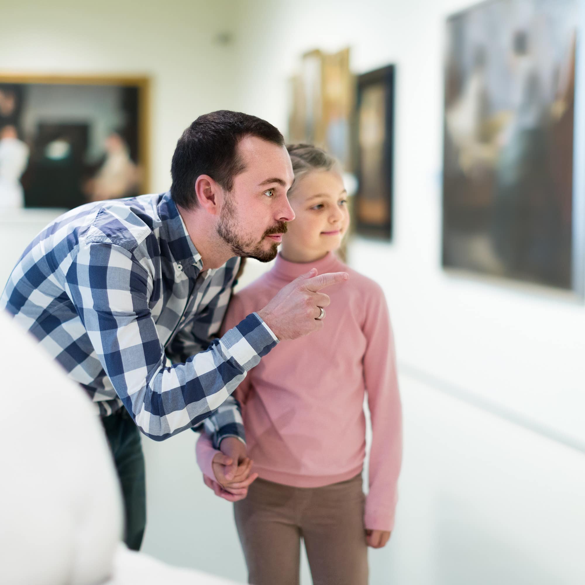 Vater und Tochter betrachten die Kunstwerke in einer Galerie