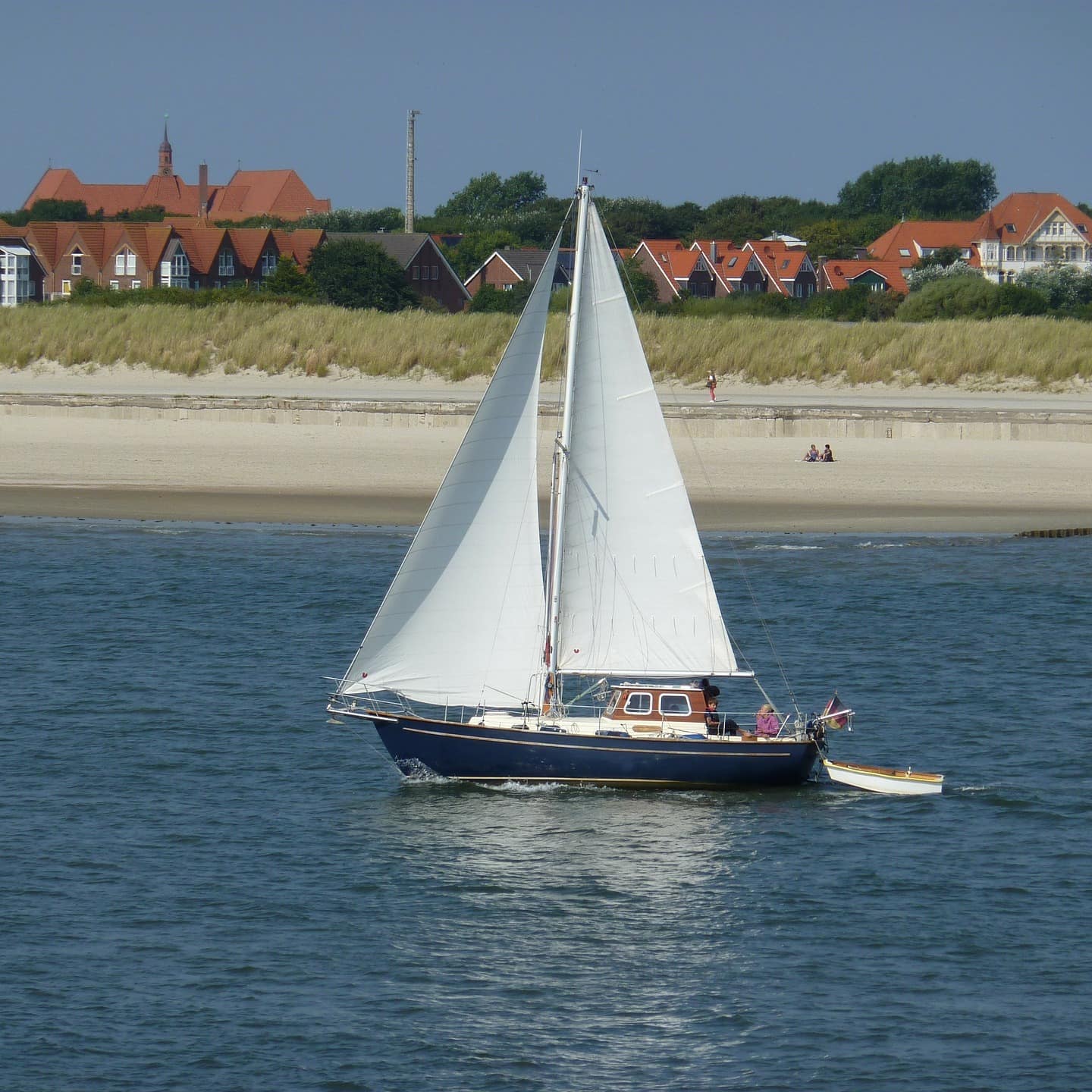 Ein Segelboot im Wasser, im Hintergrund sind Häuser von Norderney zu sehen