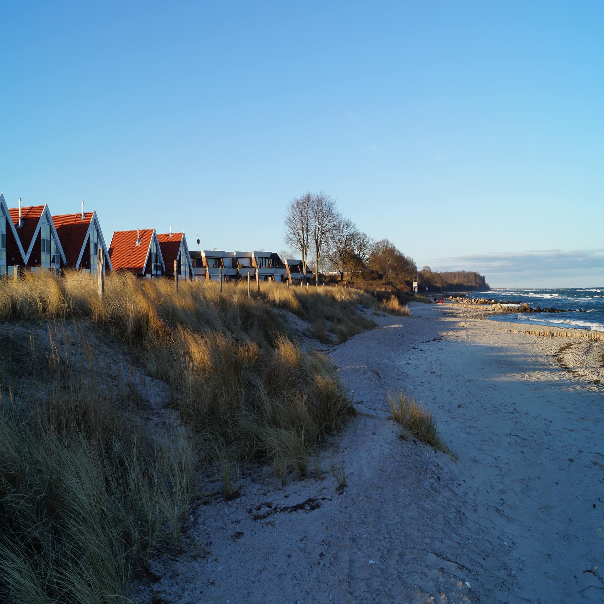 Einige kleine Häuser direkt am Strand, rechts am Meer.