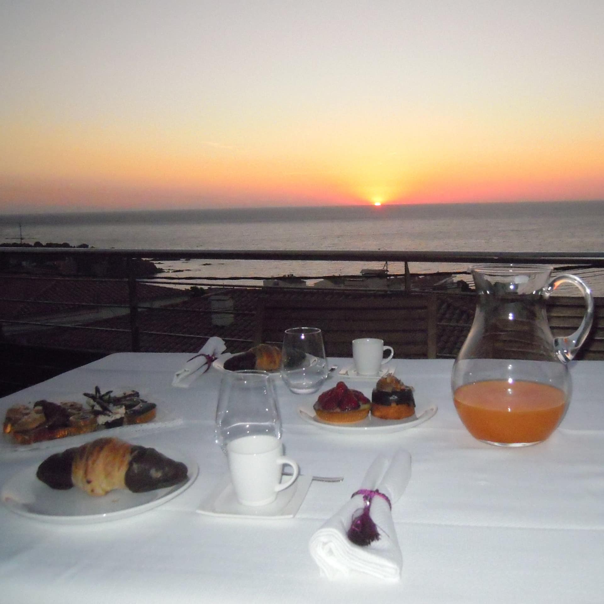 Ferienwohnung an der Costa Brava mit Balkon, darauf ein gedeckter Frühstückstisch und Blick auf den Sonnenaufgang