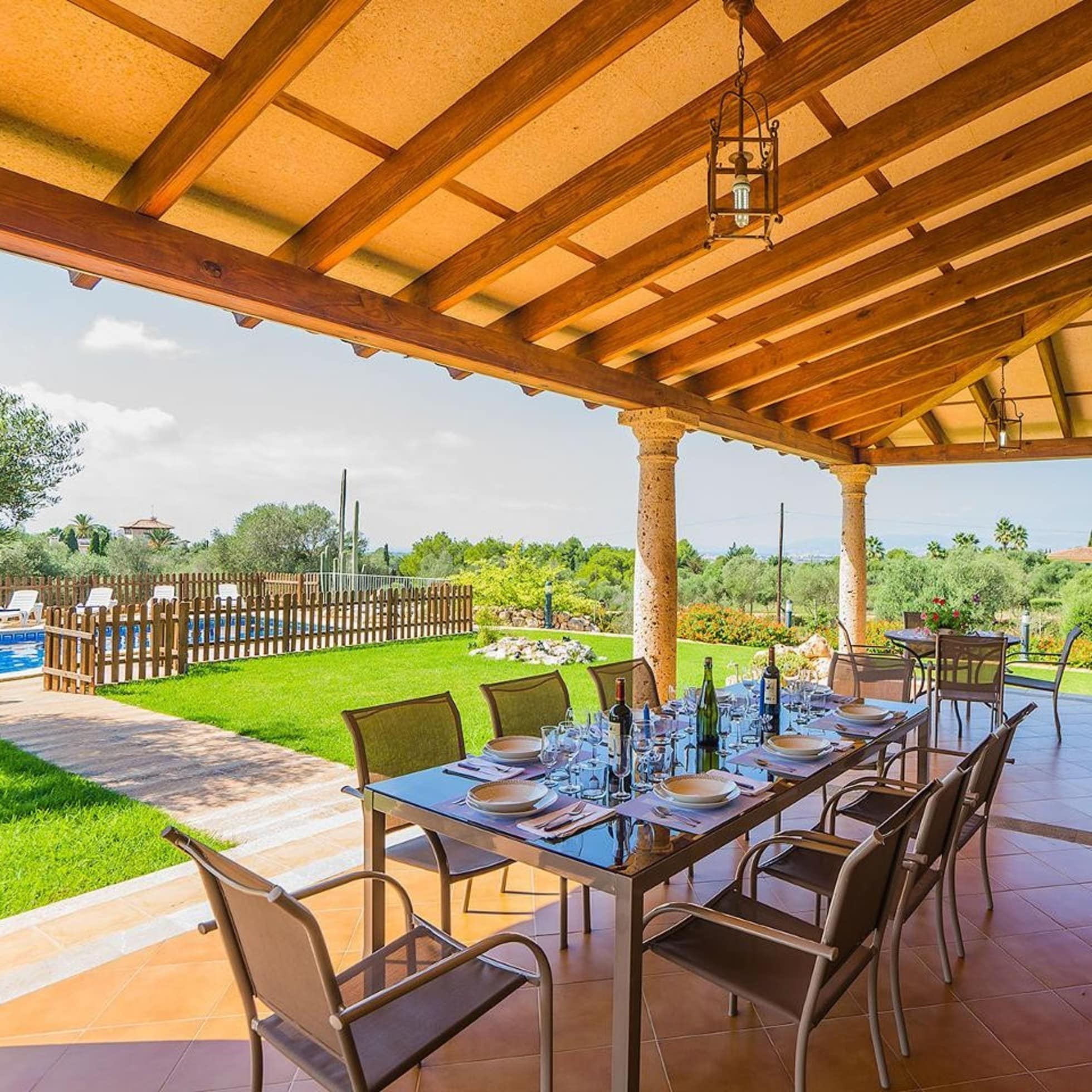 Blick von der Terrasse mit gedecktem Tisch auf den Garten mit eingezäuntem Pool