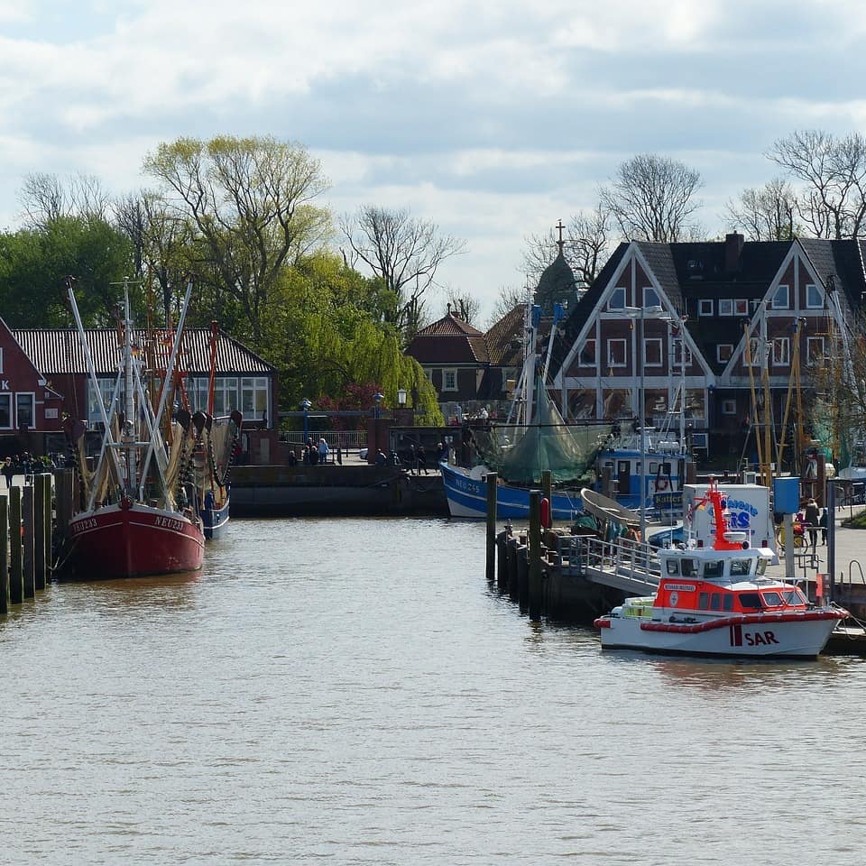 Das Hafenbecken von Neuharlingersiel mit Booten, einer Promenade und Häusern im Hintergrund