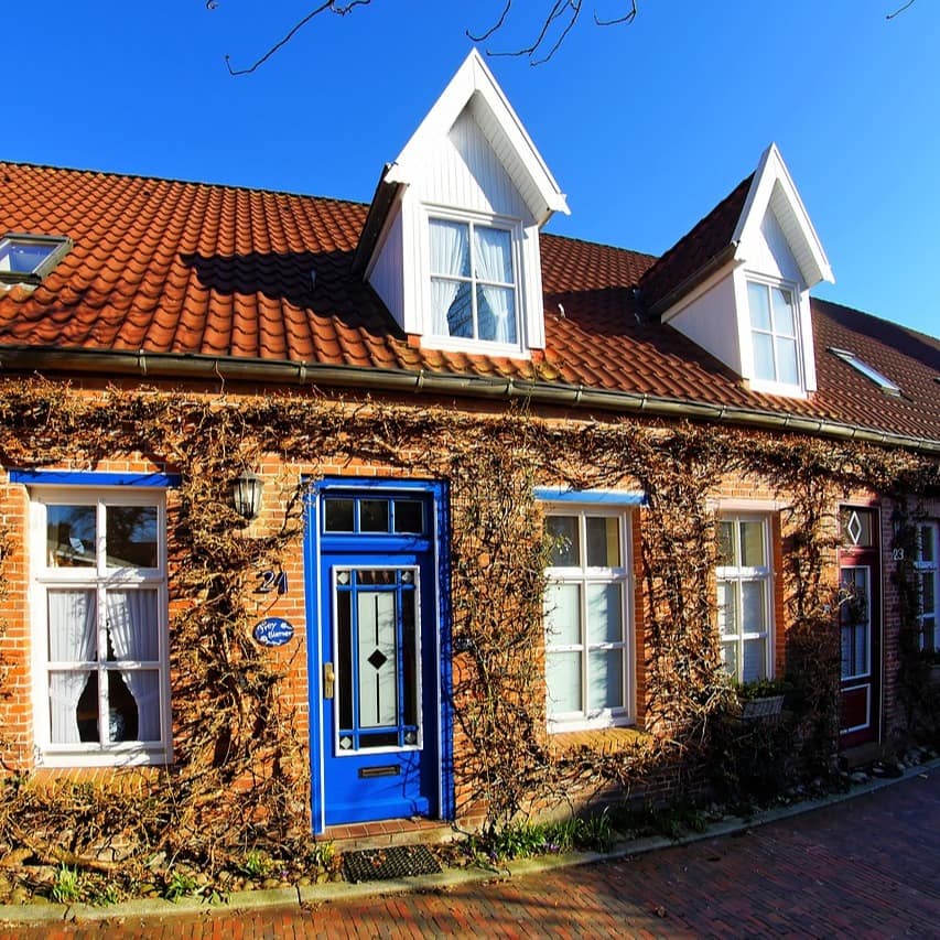 Din Friesenhaus mit Sprossenfenstern und blauer Tür