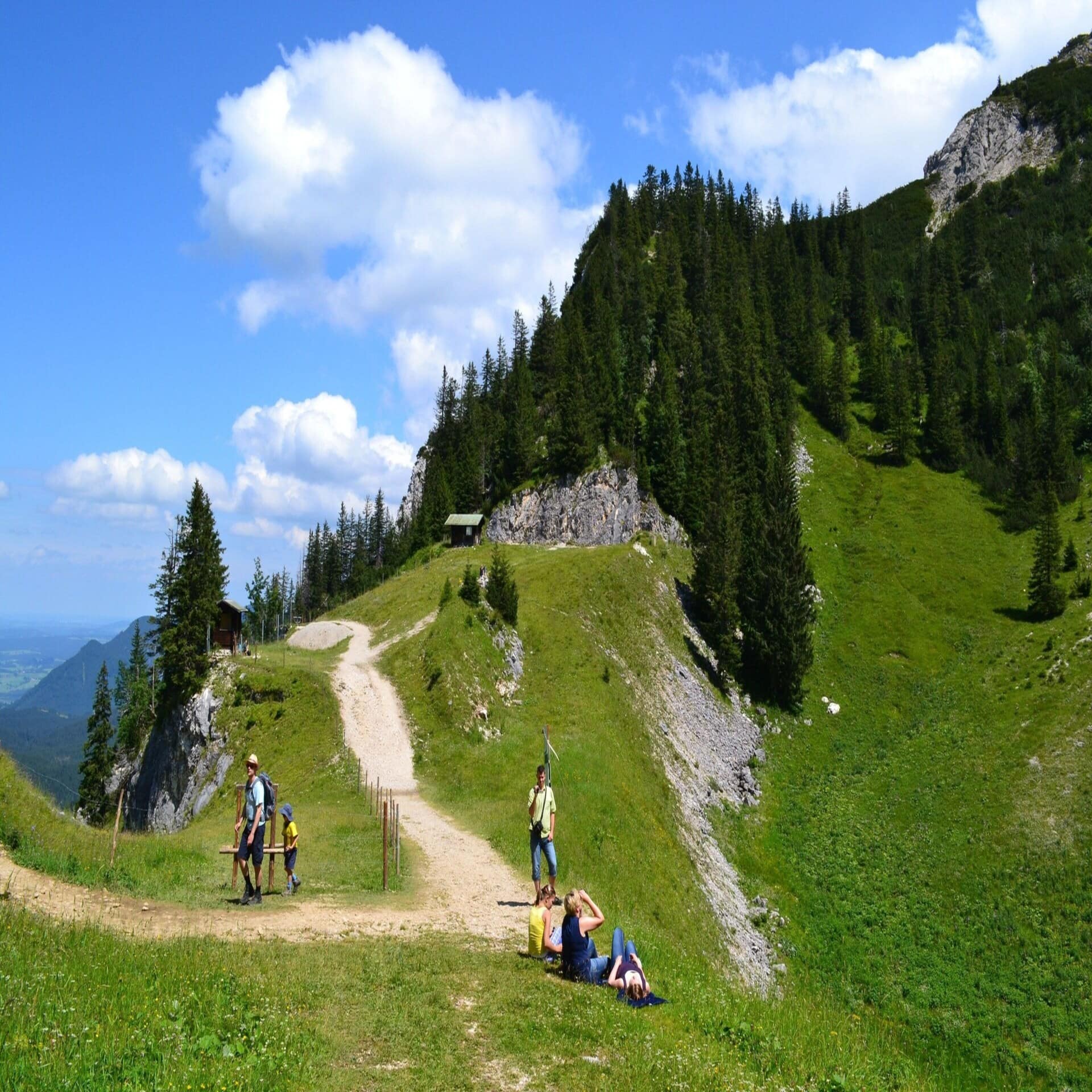 Personen auf einem bergigen Wanderweg im Allgäu im Sommer. 
