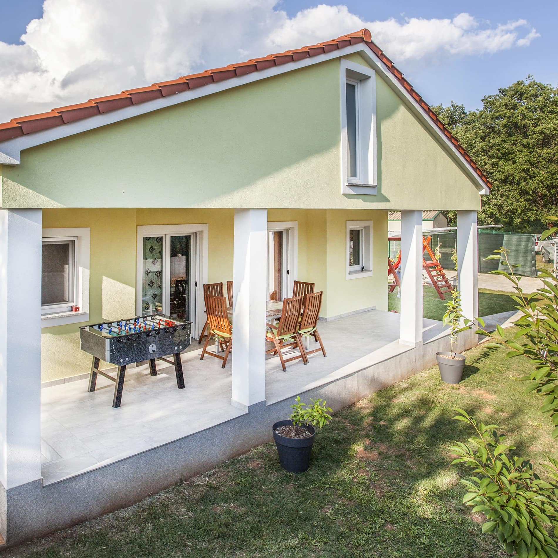 Ferienhaus in Pula mit Tischfußballkasten und Tisch auf einer Terrasse, im Hintergrund ein Wald