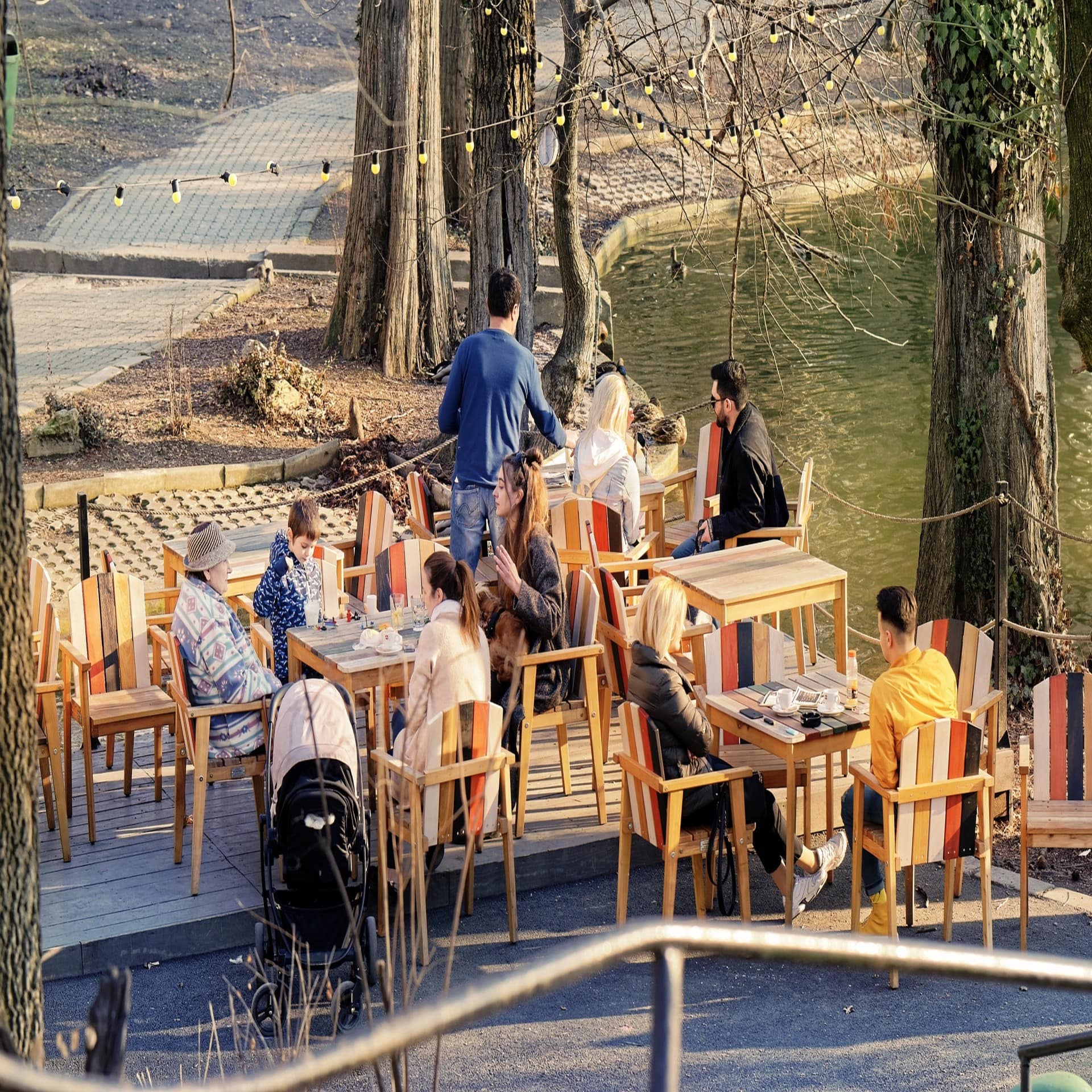 Ein Café mit Holztischen und Stühlen am Seeufer. Es ist Herbst. 