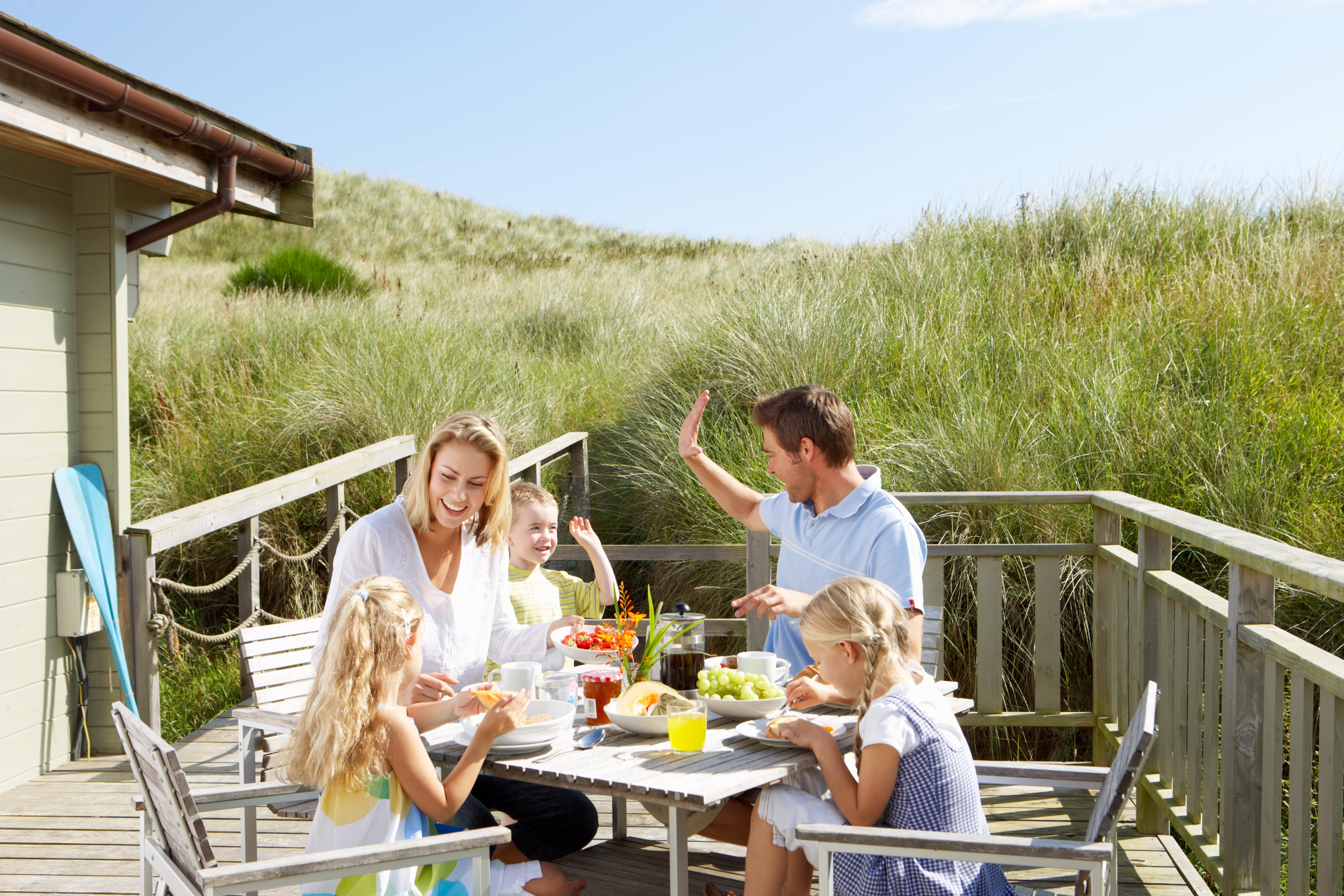 Familie, die draußen mit Dünen im Hintergrund isst