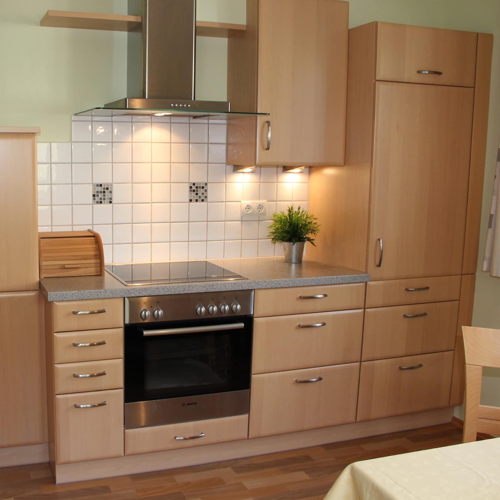 Moderne Küche einer Ferienwohnung in der Salzburger Innenstadt mit Mobiliar in hellem Holz