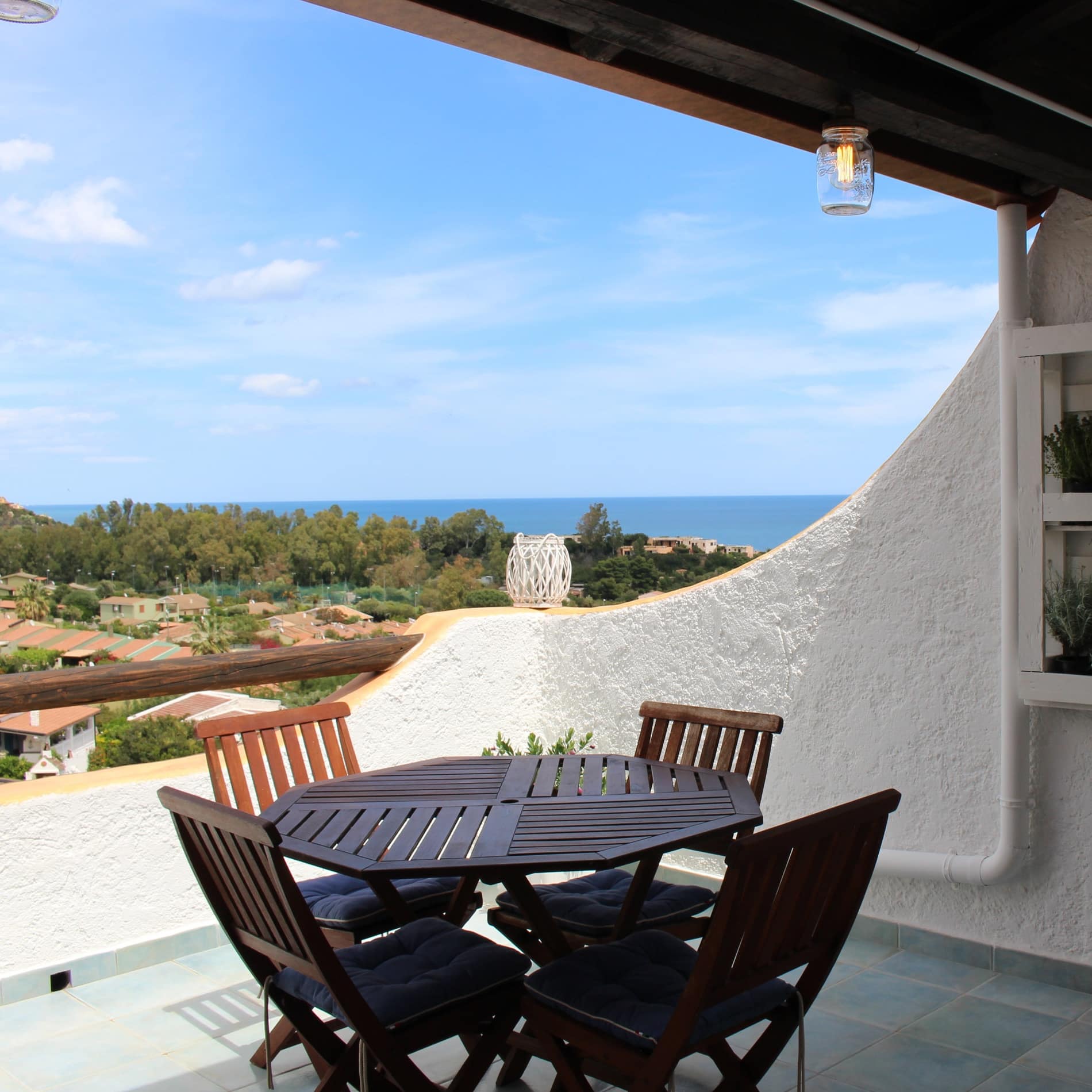 Ein Tisch mit vier Stühlen steht auf der Terrasse der Ferienwohnung in Costa Rei, von wo Sie einen herrlichen Ausblick aufs Meer genießen