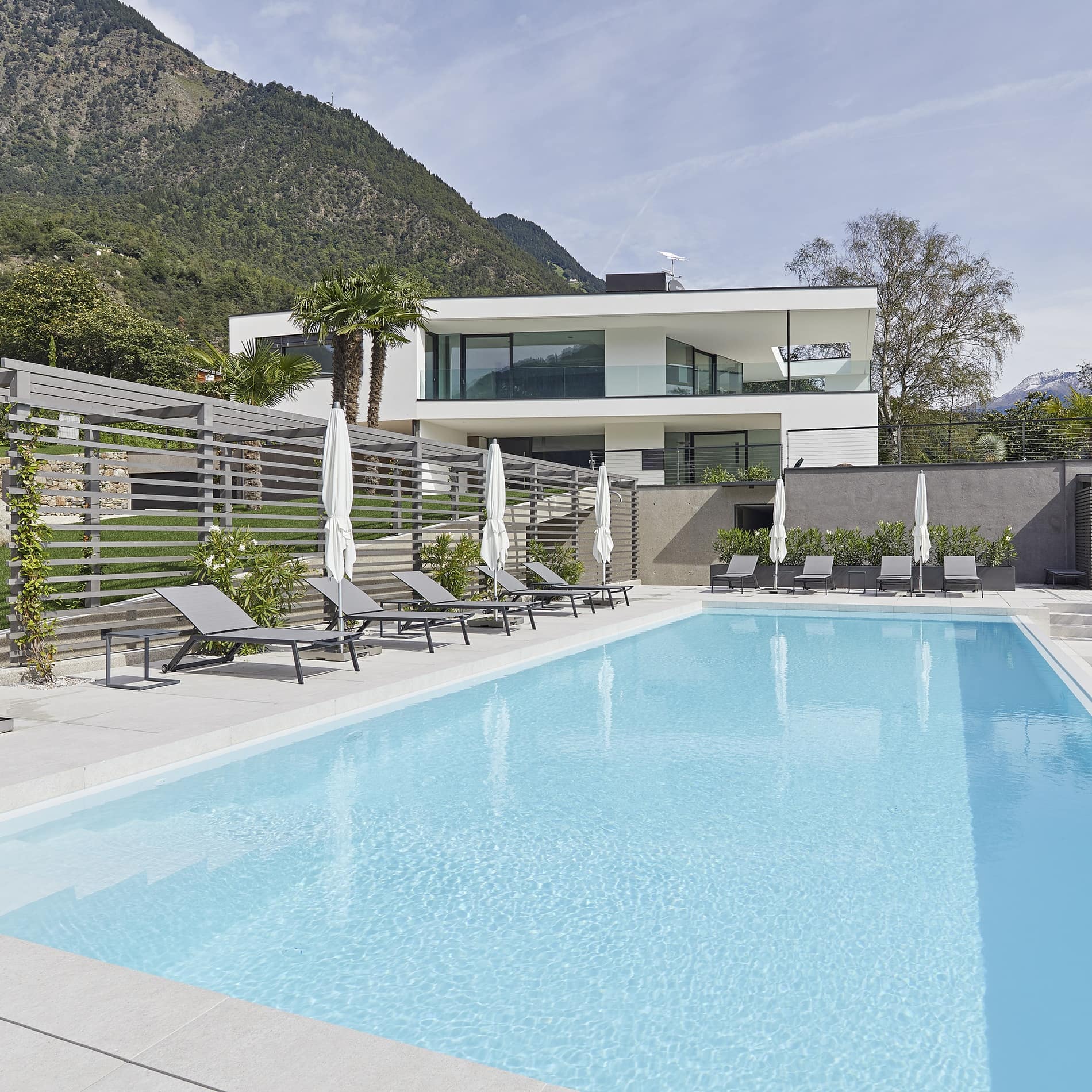 Am Pool der Ferienwohnung in Algund stehen elegante Sonnenliegen: eine mondäne Ferienwohnung in Italien mit Pool