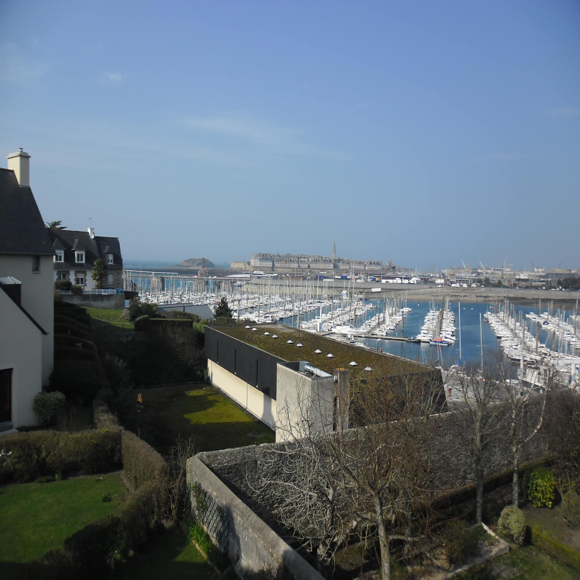 Blick über Gärten auf einen kleinen Hafen und Saint-Malo.