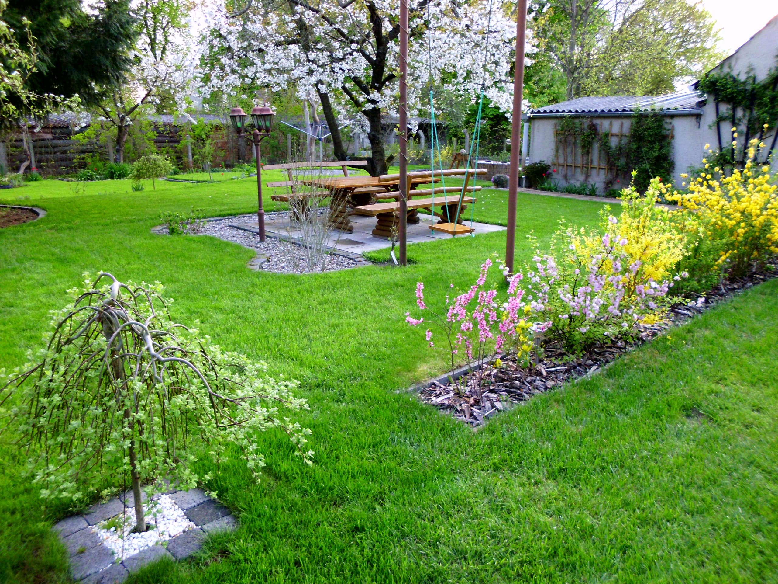 Blühender Frühlingsgarten mit Schaukel und Sitzgelegenheiten einer hundefreundlichen Ferienwohnung in Waren/Müritz