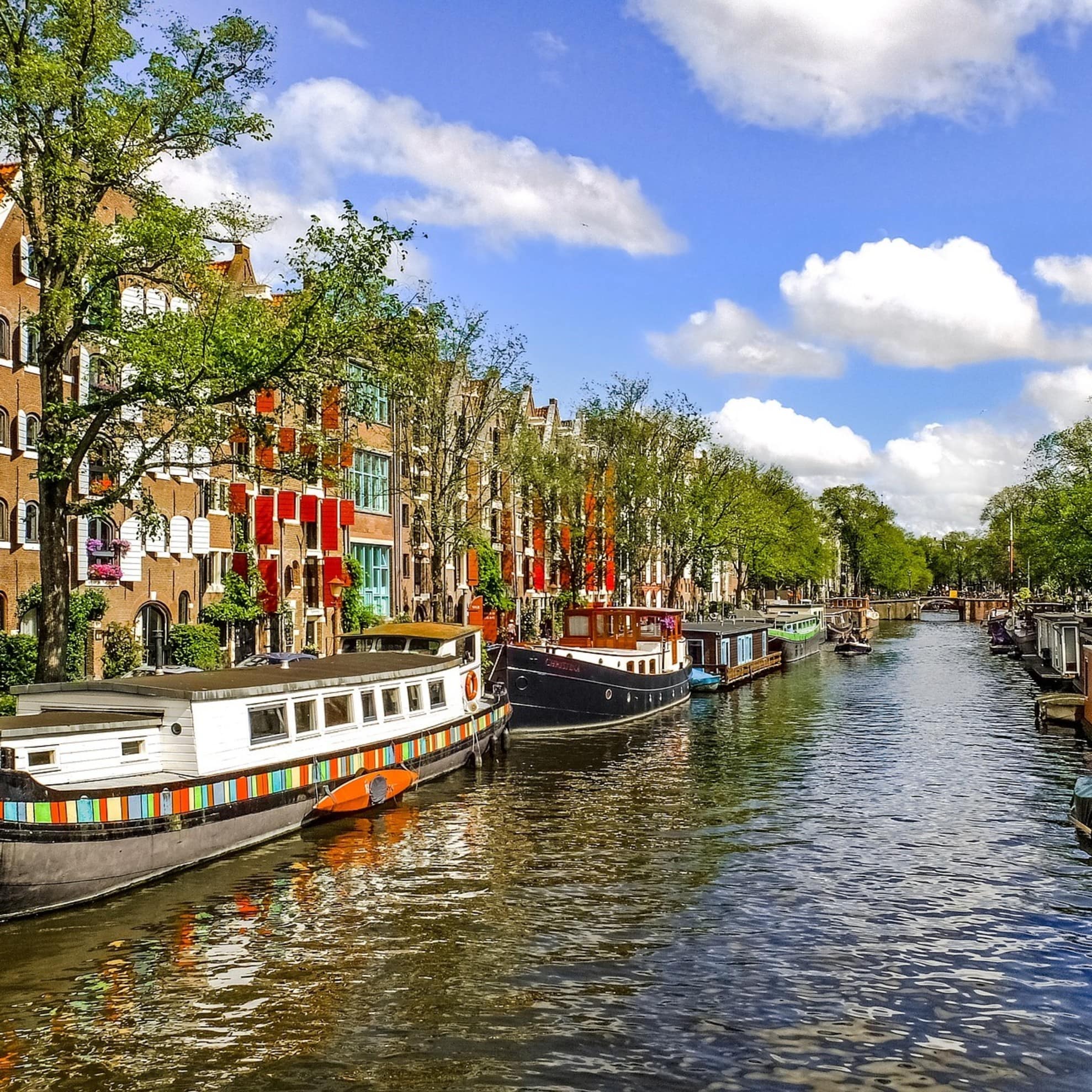 Häuser in Amsterdam direkt am Kanal, auf dem Lastenkähne schwimmen