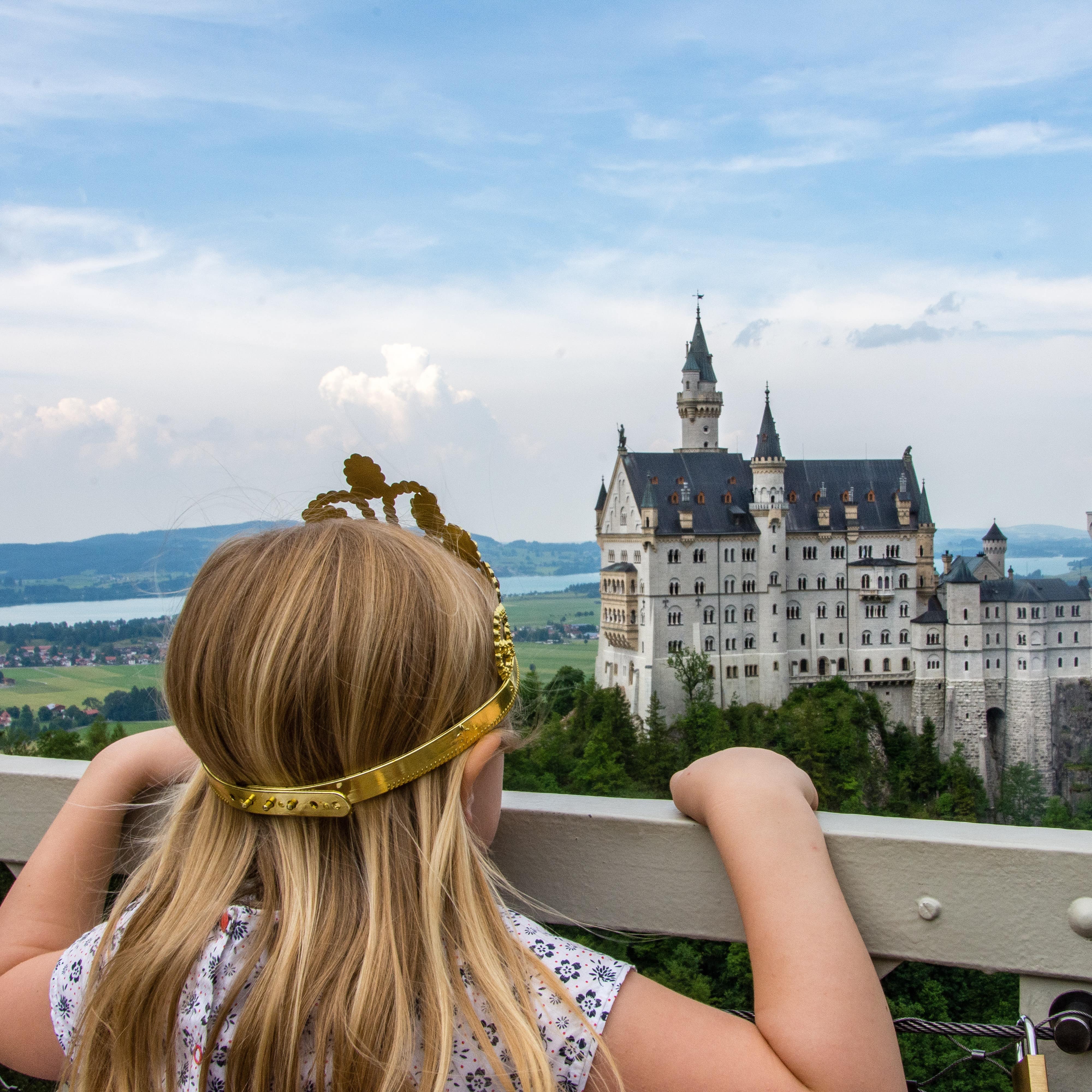 Ein Mädchen blickt von einem Aussichtspunkt auf das Schloss Neuschwanstein