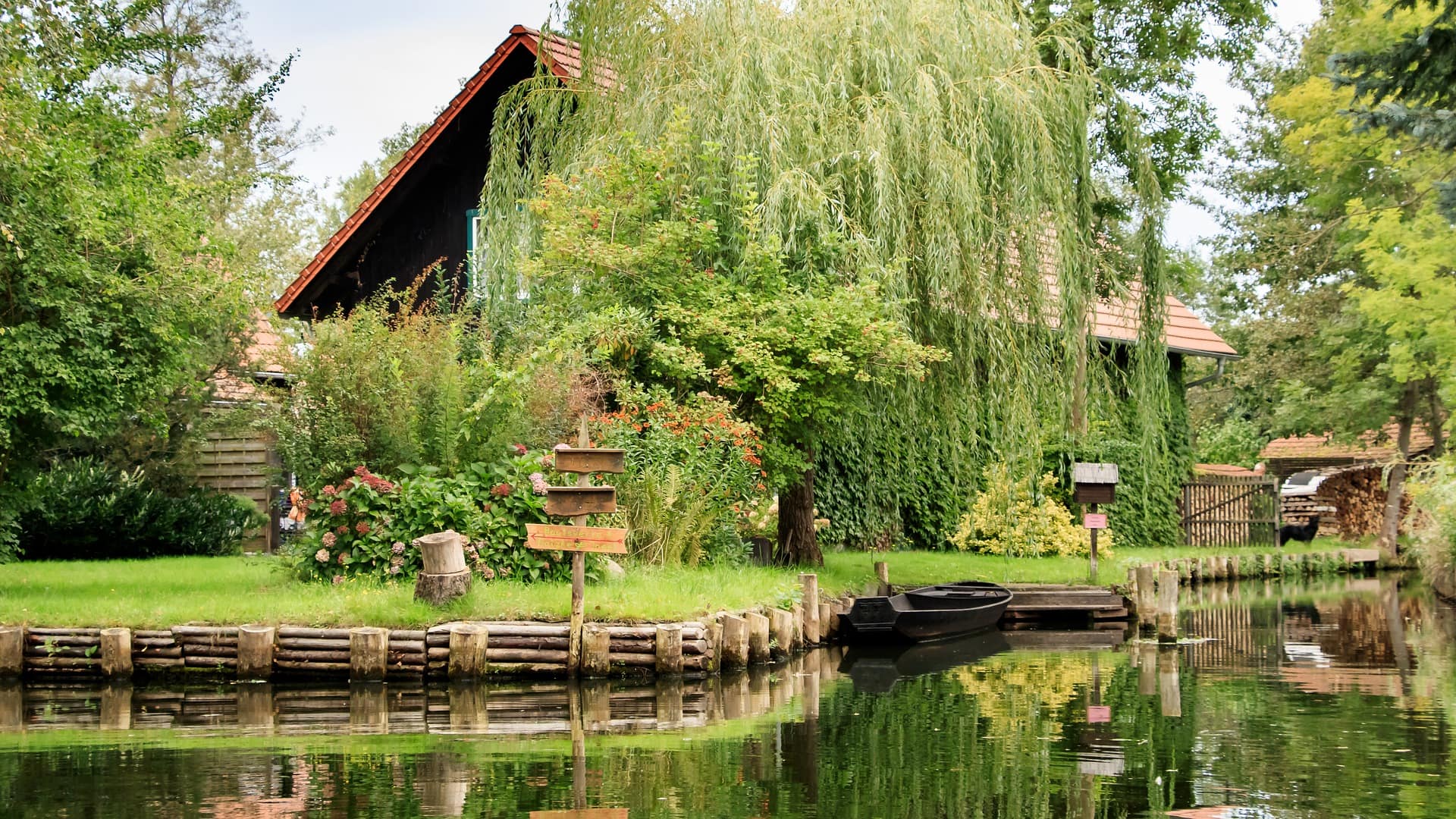 Freistehendes großes Ferienhaus mit Garten direkt am Wasser, das Haus ist von einem Baum verdeckt