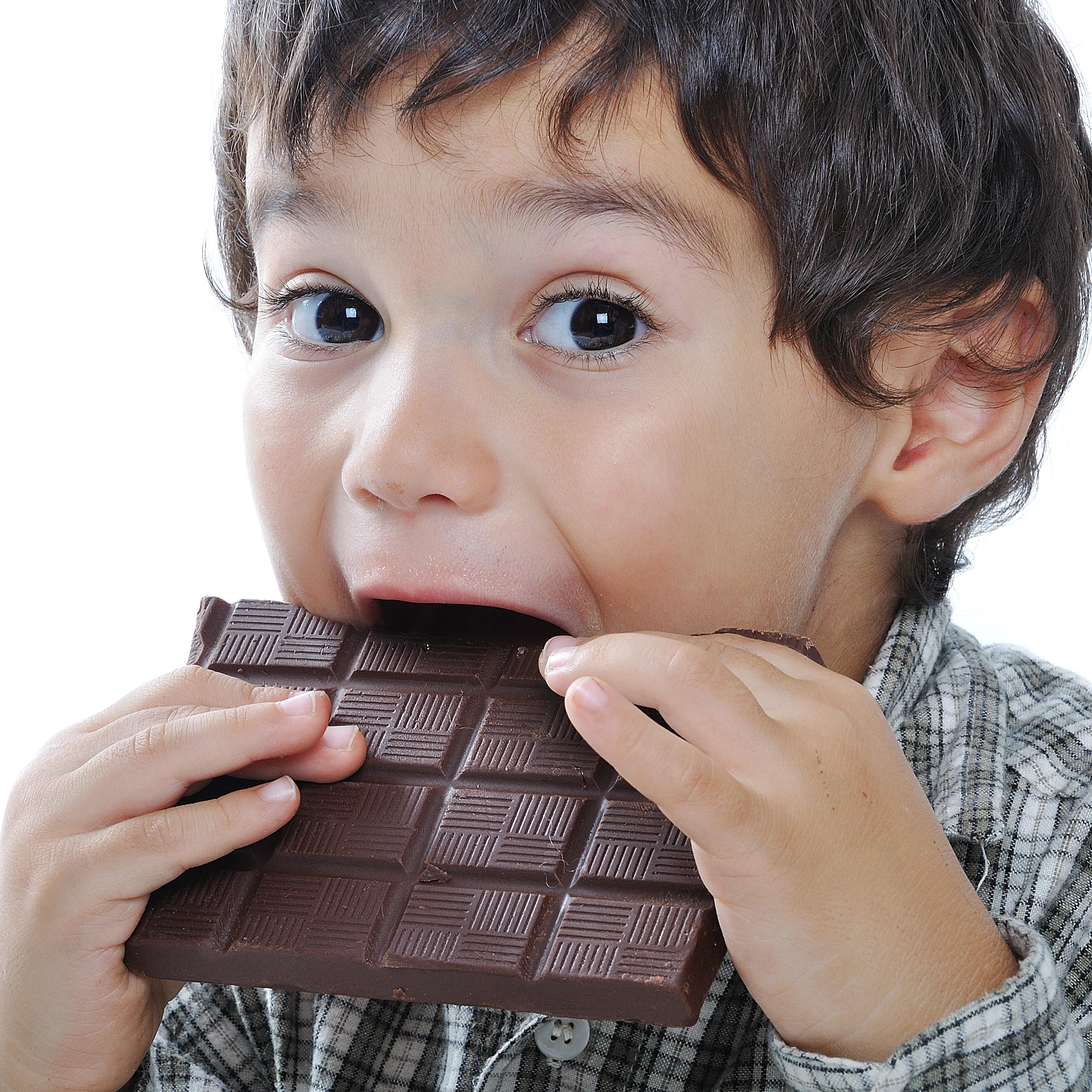 Kleinkind mit blau-gestreiftem Pulli vor eine Tasse Schokolade mit Gesicht draft. Der Junge grinst. 